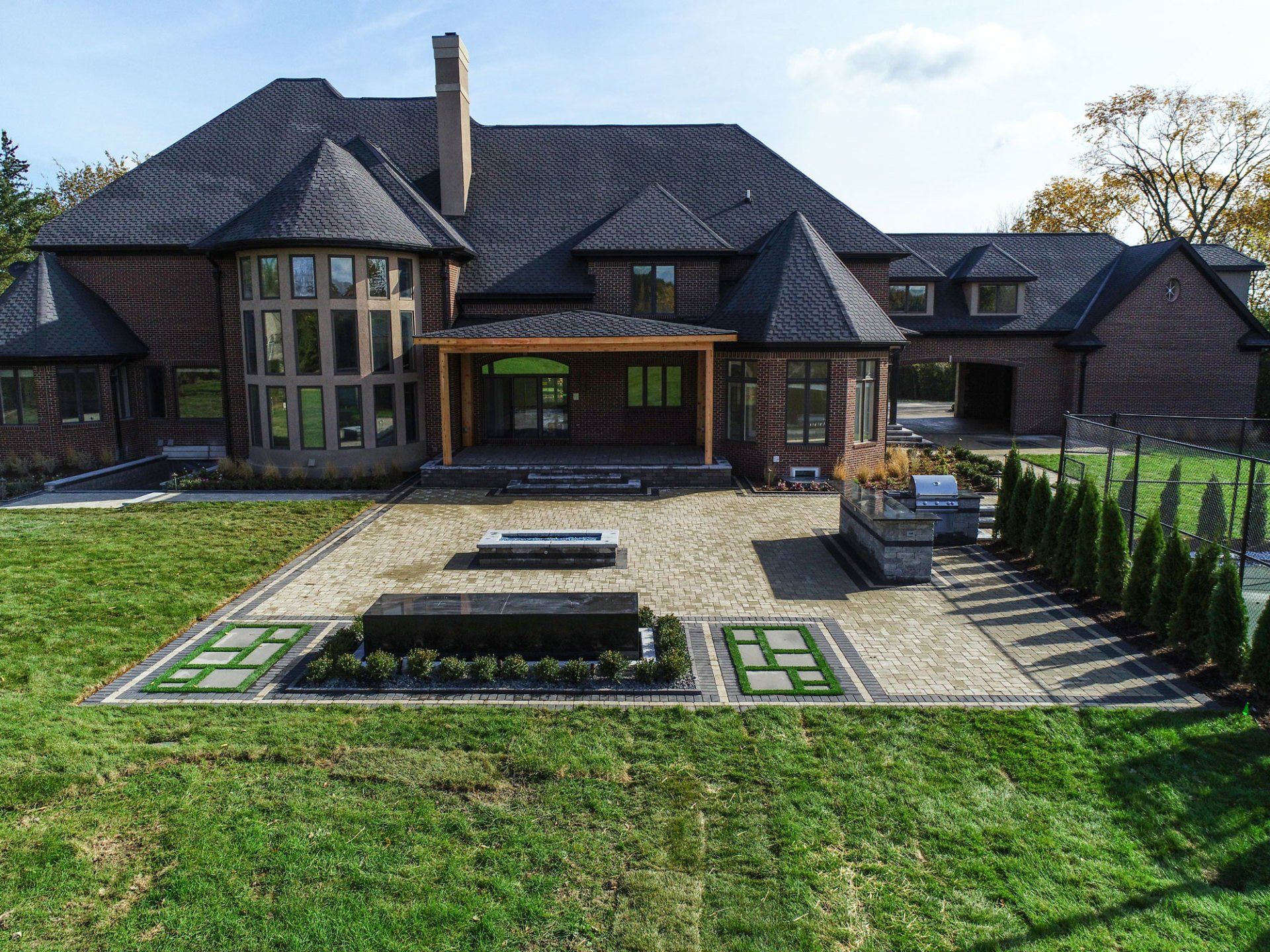 An aerial view of a large brick house with a large lawn in front of it.