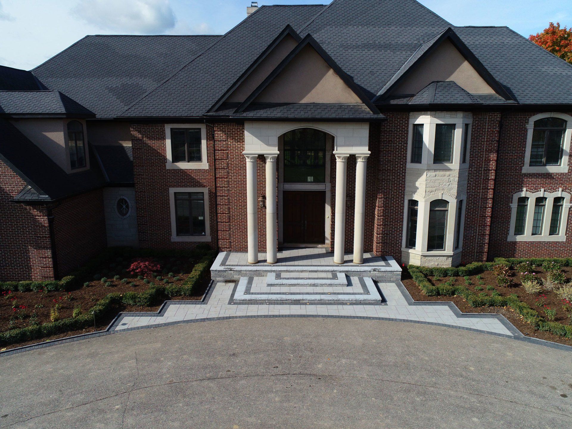 An aerial view of a large brick house with a black roof