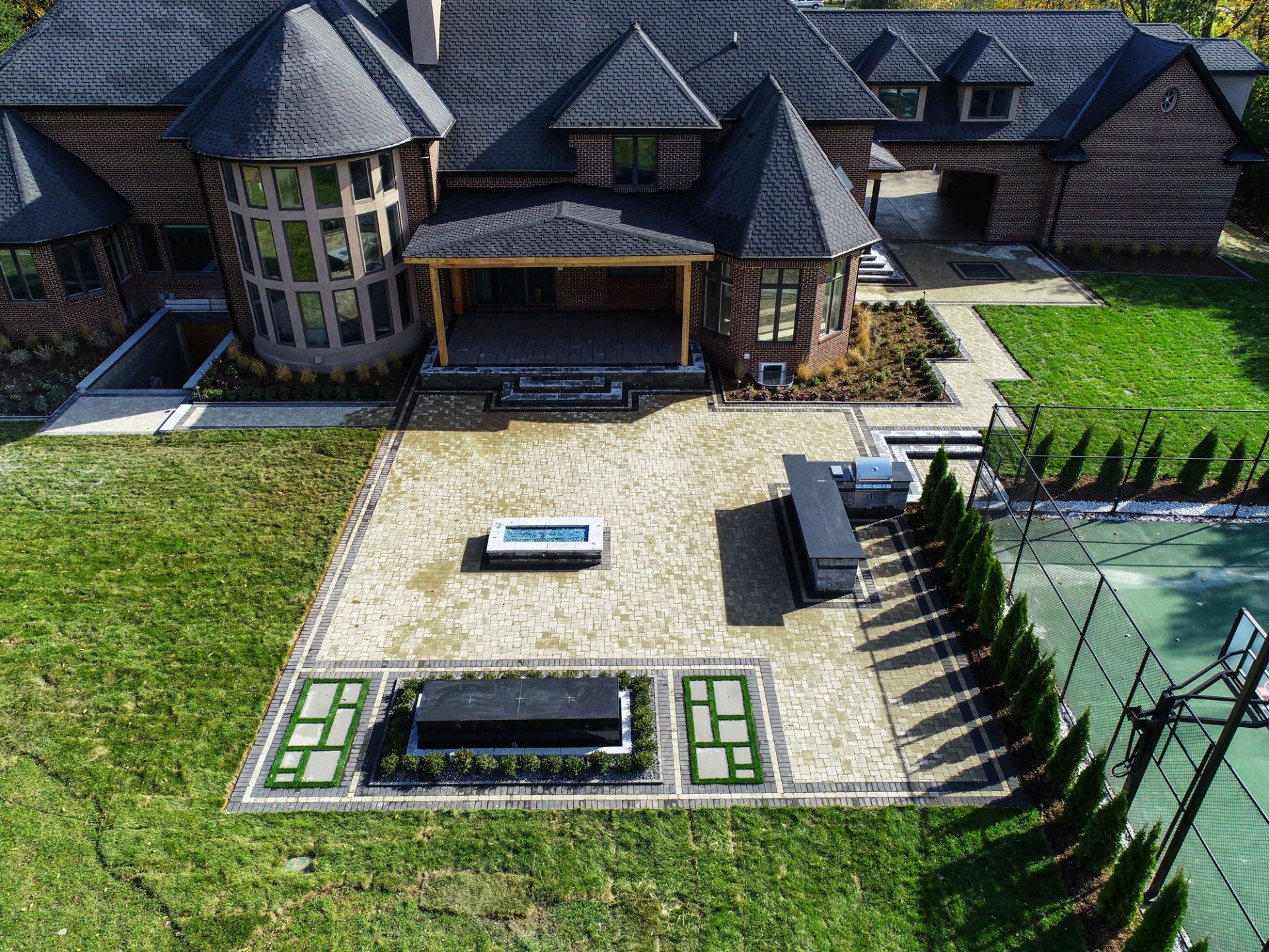 An aerial view of a large house with a tennis court in front of it.