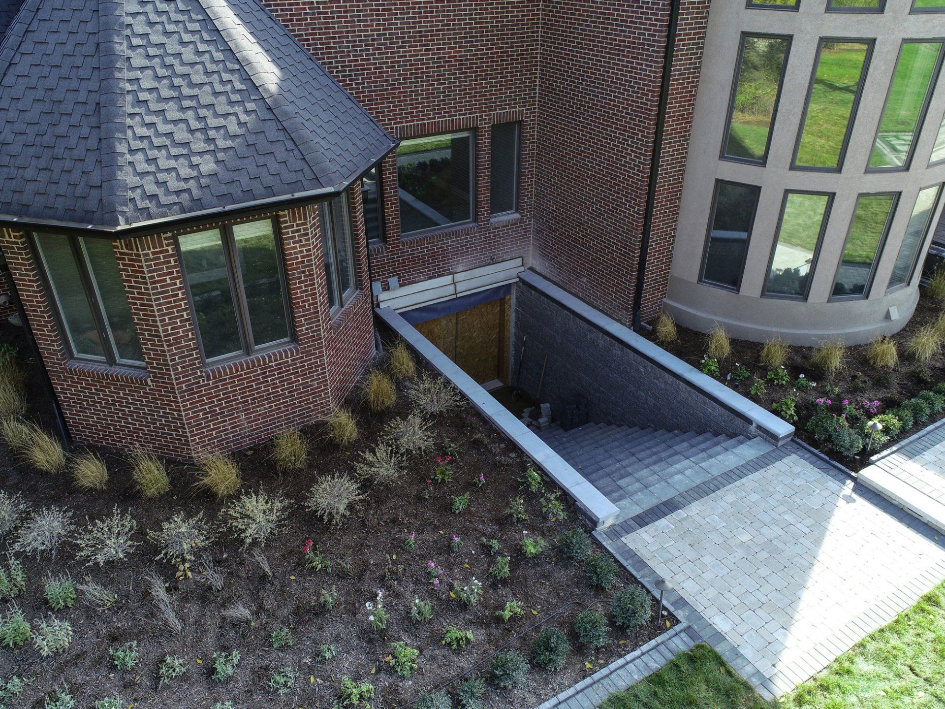 An aerial view of a brick house with a walkway leading to it
