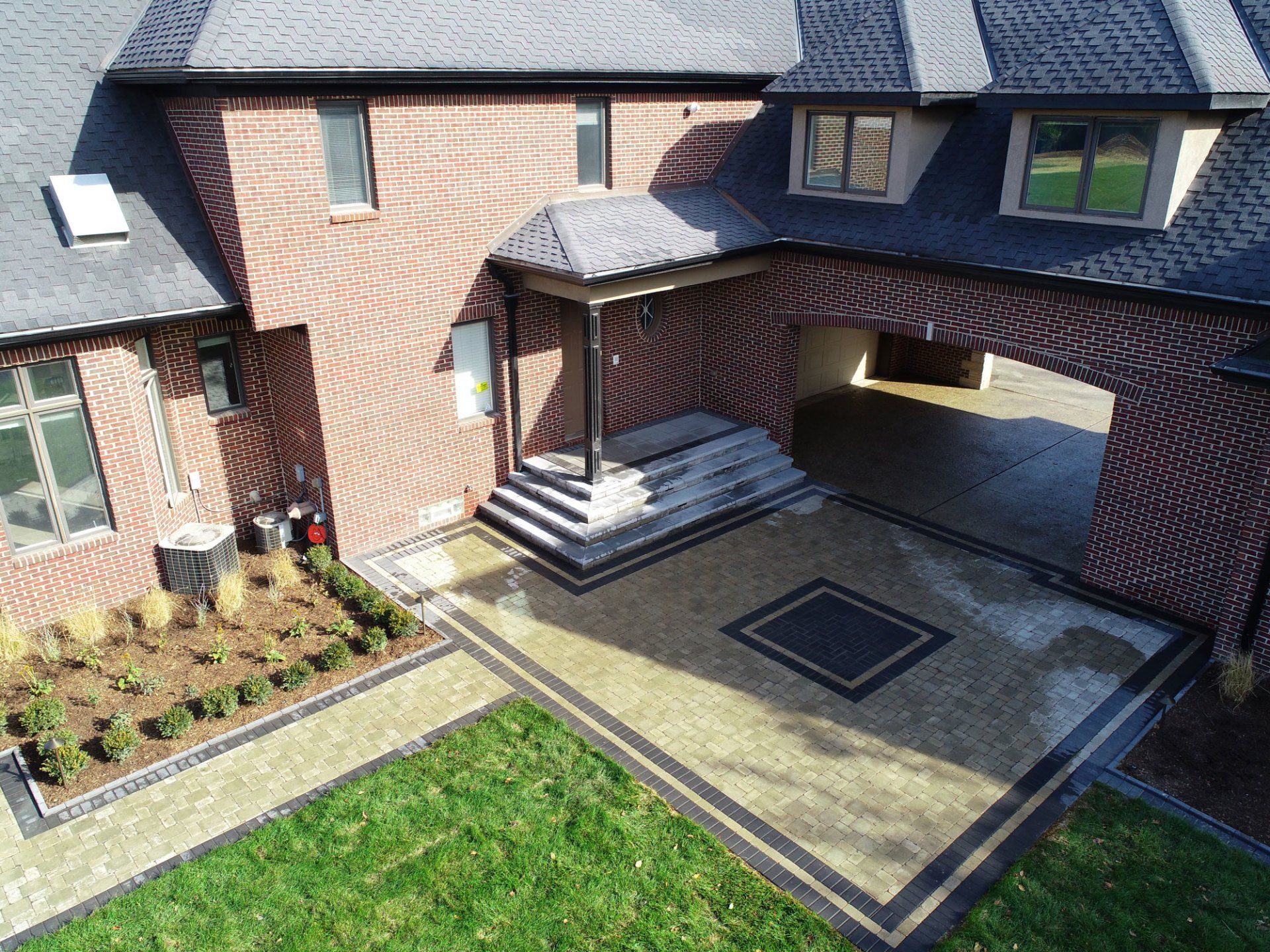 An aerial view of a large brick house with a driveway leading to it.