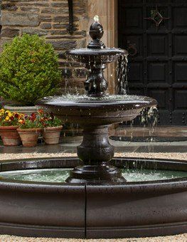 a large fountain is sitting in front of a stone building .