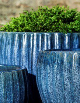 three blue pots with green plants in them are sitting on a table .