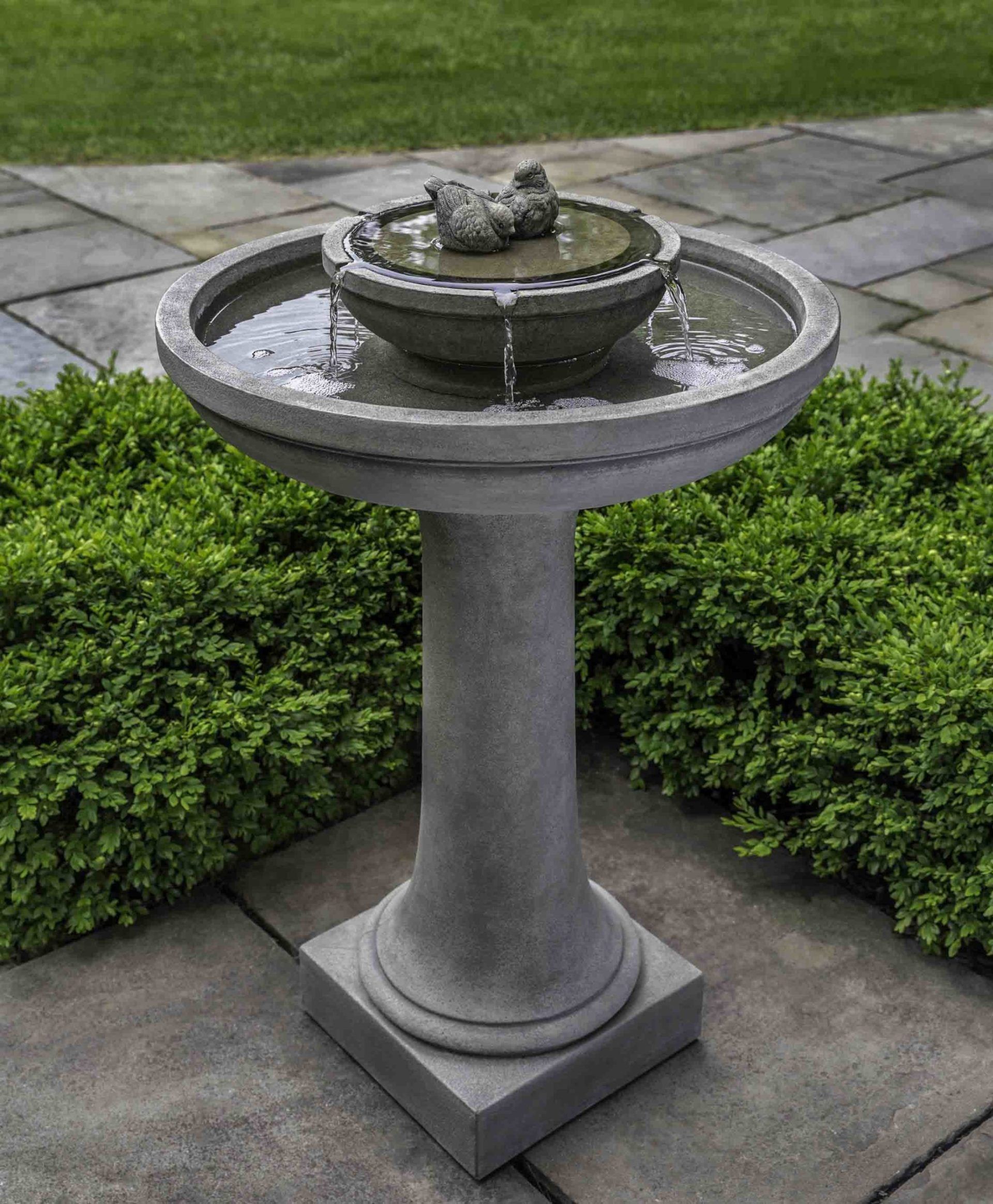 a bird bath on a pedestal in a garden