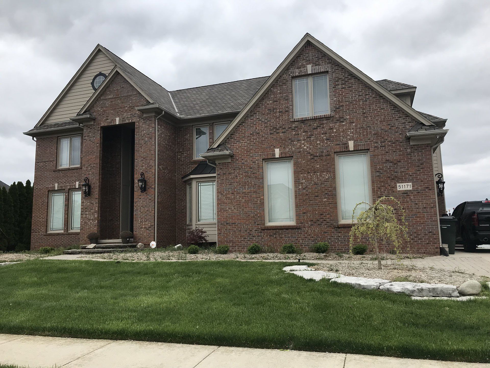 A large old brick house with a lot of windows is sitting on top of a lush green lawn.