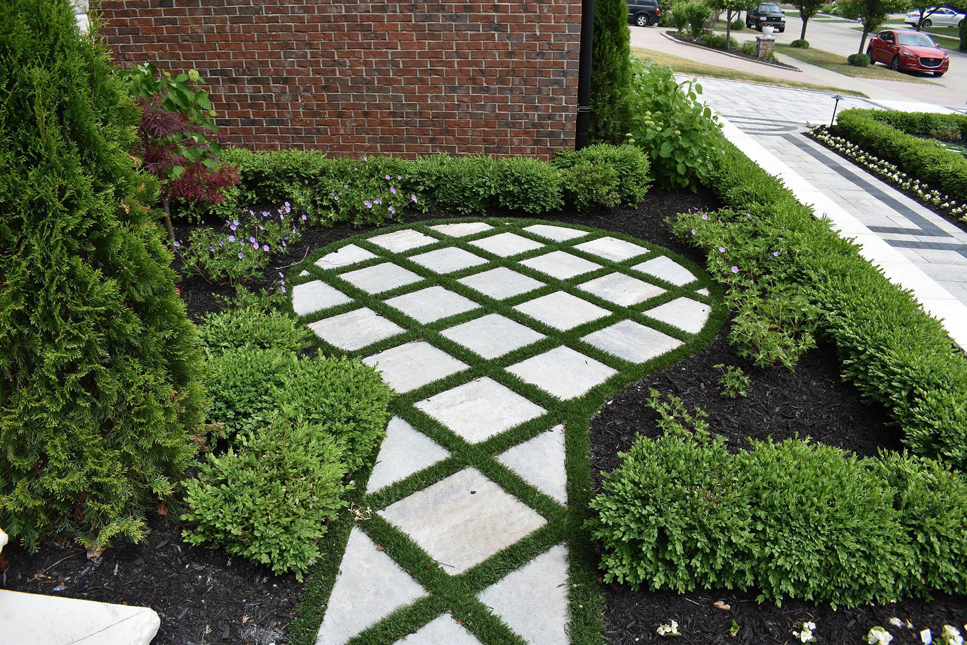 A stone walkway in a garden with a brick wall in the background.