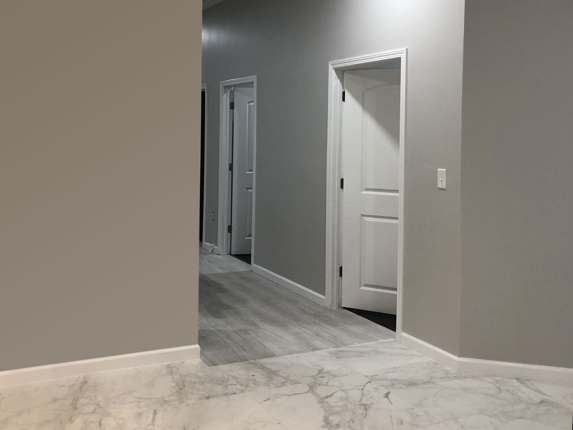 A hallway with gray walls and white doors in a house.