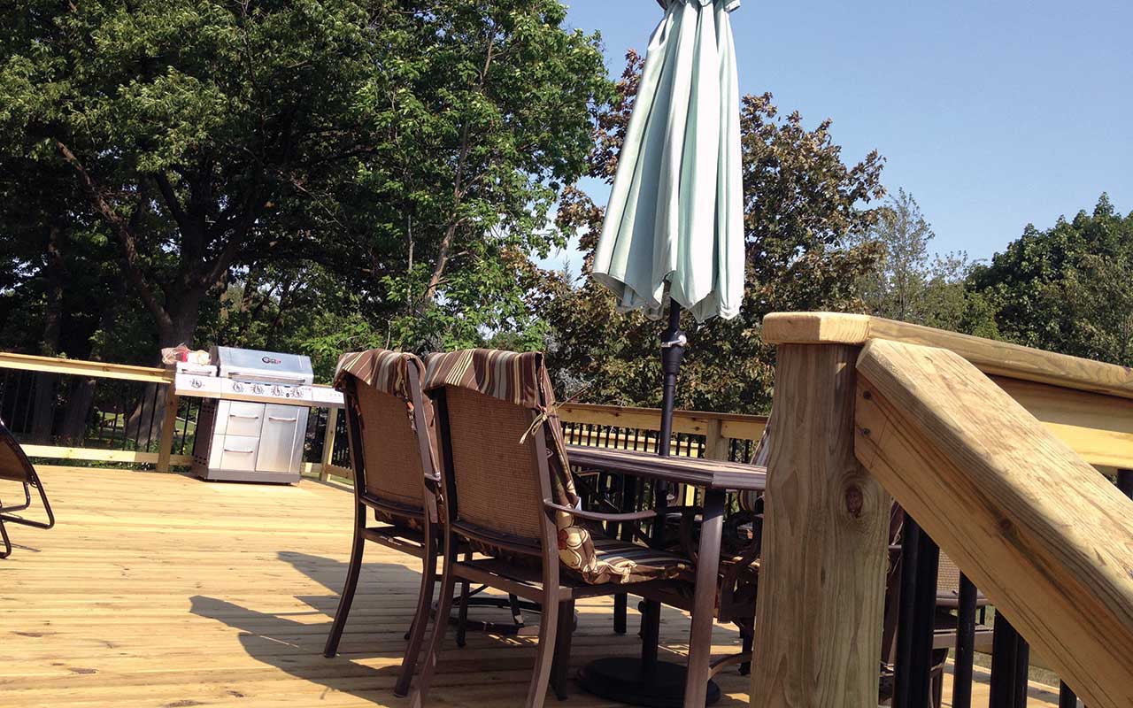 a wooden deck with a table and chairs and an umbrella