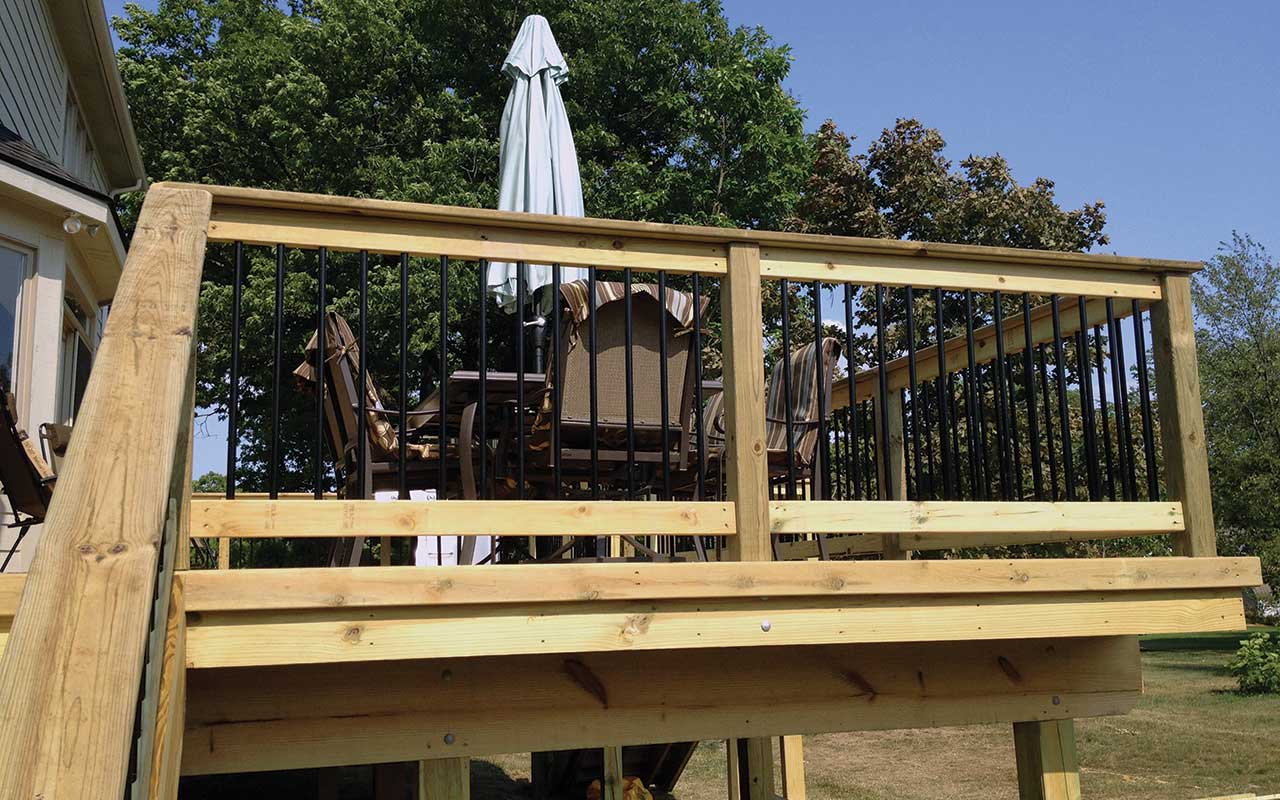 a wooden deck with a table and chairs and an umbrella .