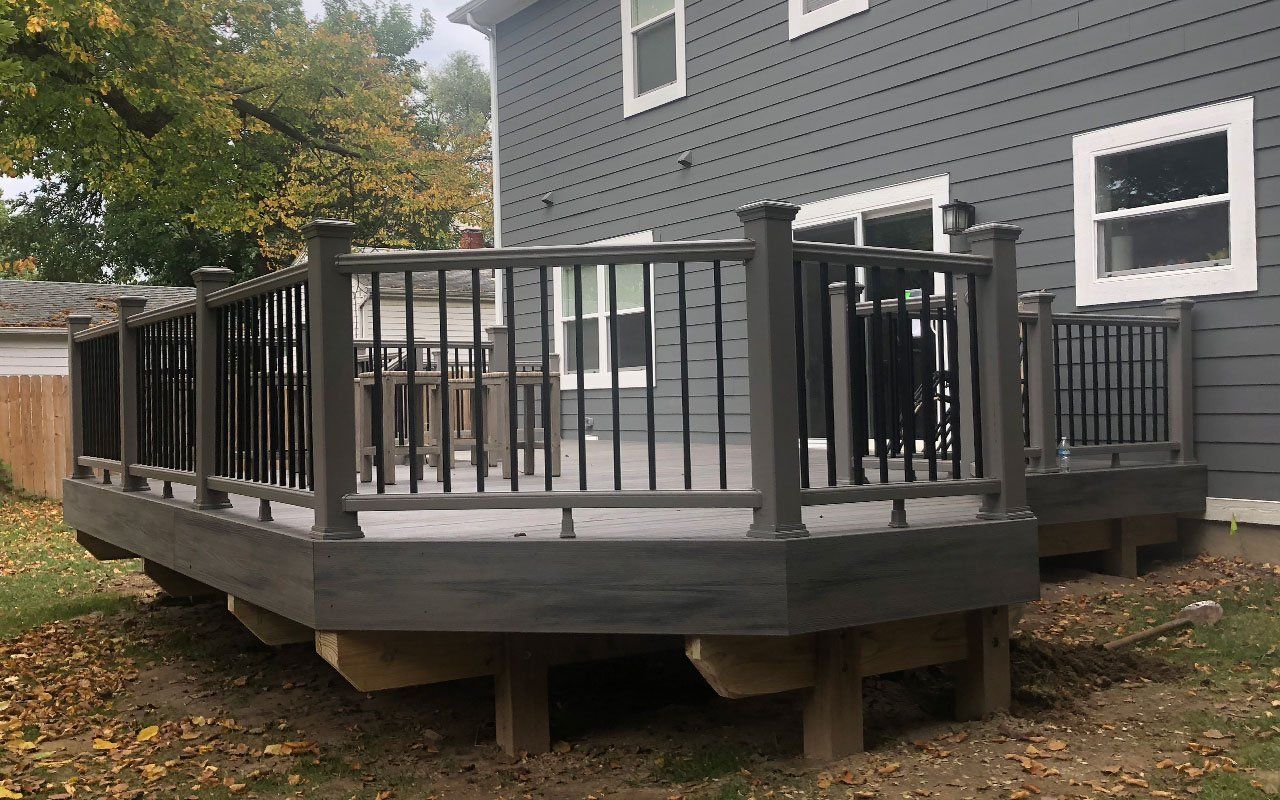 a gray deck with a black railing is in front of a gray house .