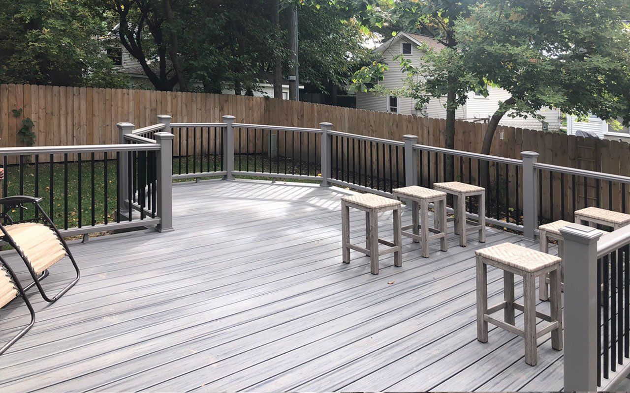 a wooden deck with stools and a chair on it .