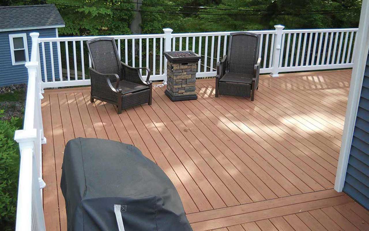 a wooden deck with chairs and a grill on it