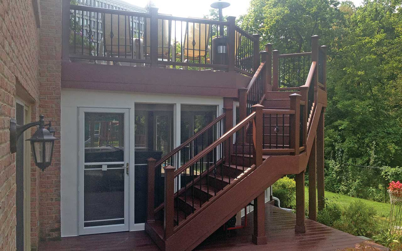 a wooden deck with stairs leading up to the second floor of a house .