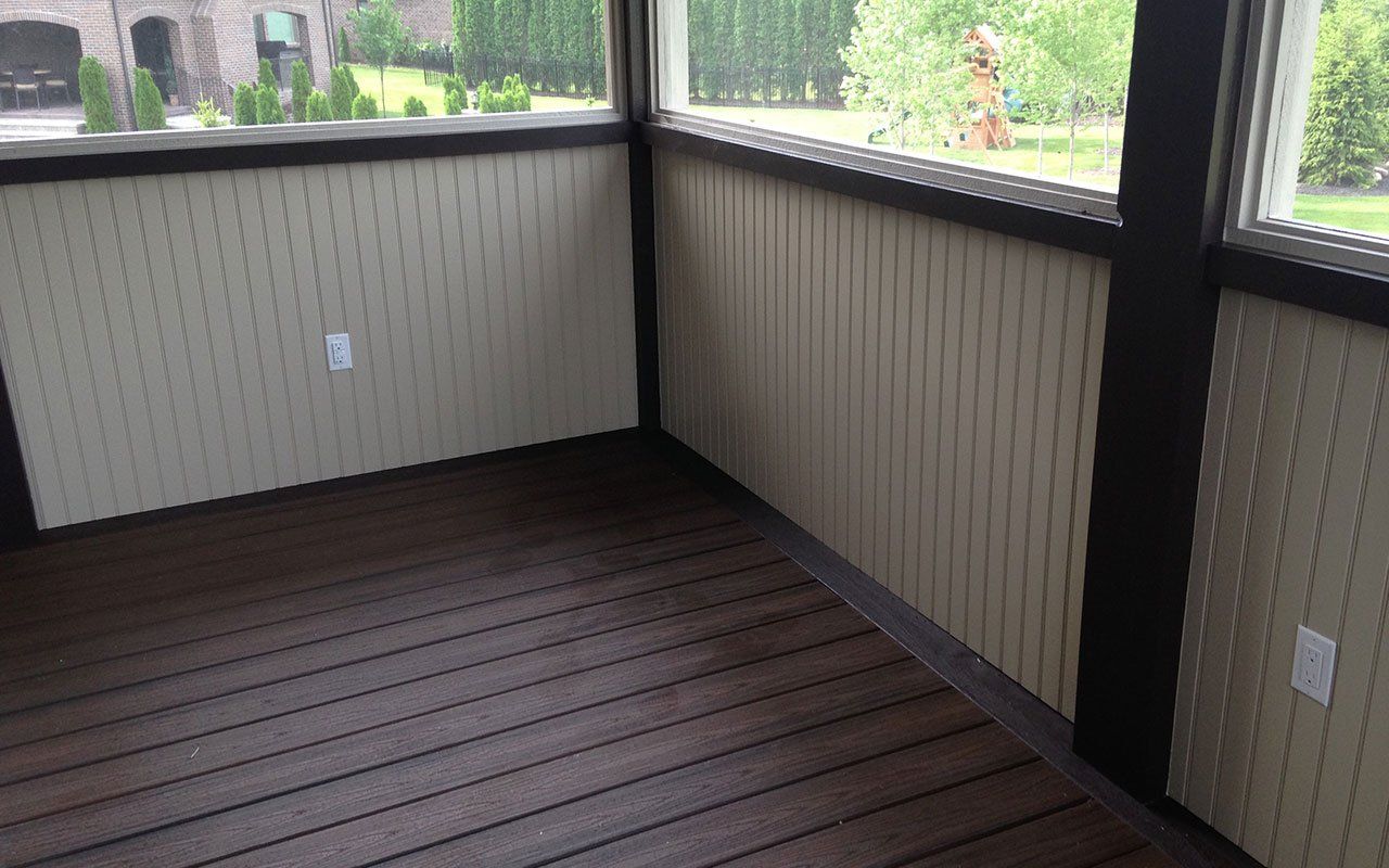 a screened in porch with a wooden floor and a window .