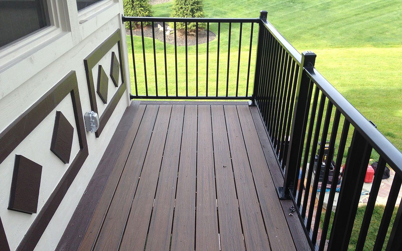 a balcony with a black railing and a wooden deck