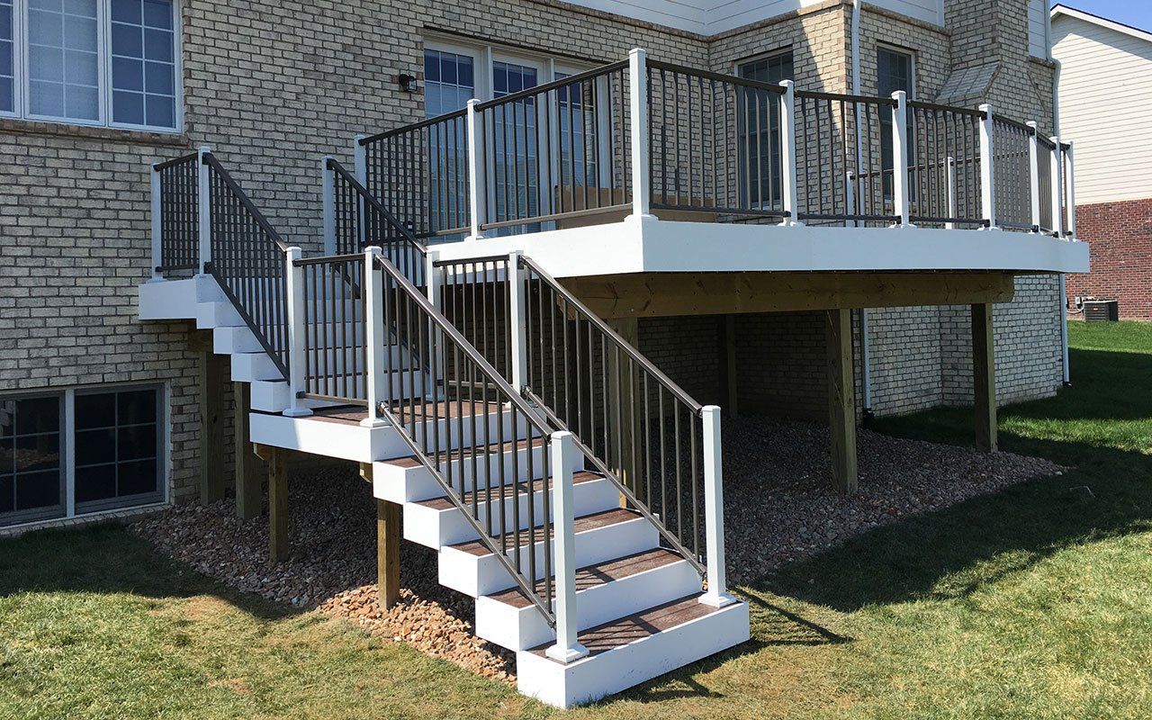 a deck with stairs leading up to it is in front of a brick house .