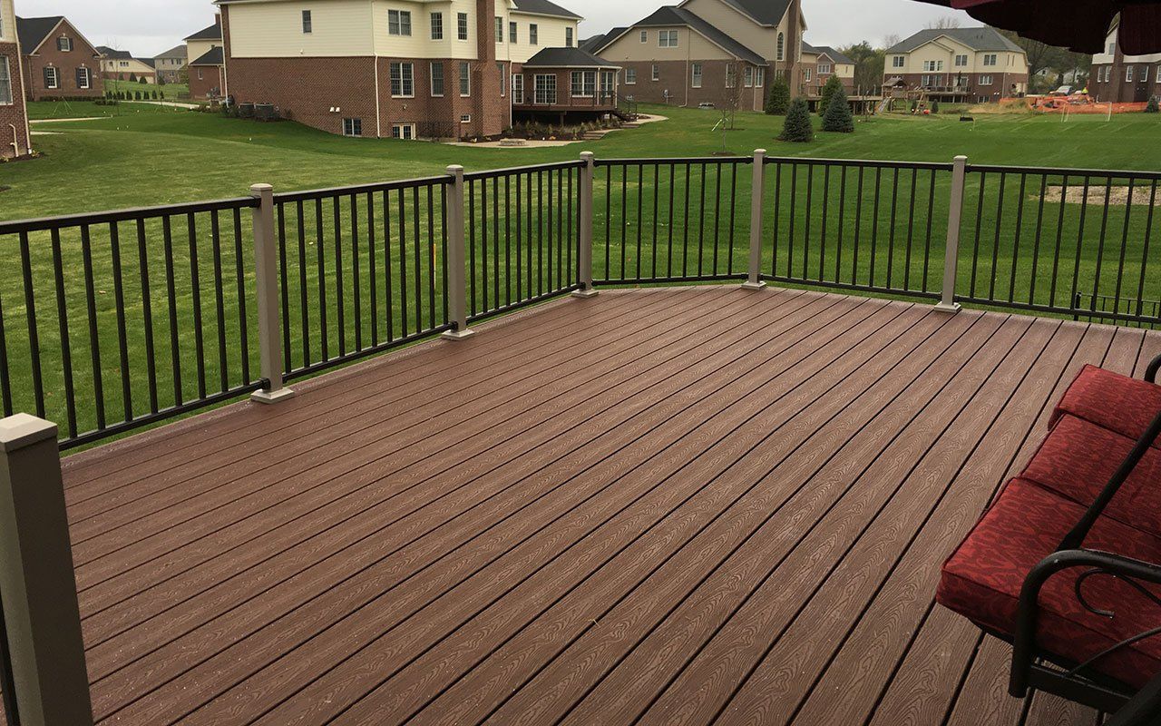 a wooden deck with a metal railing and a red couch .
