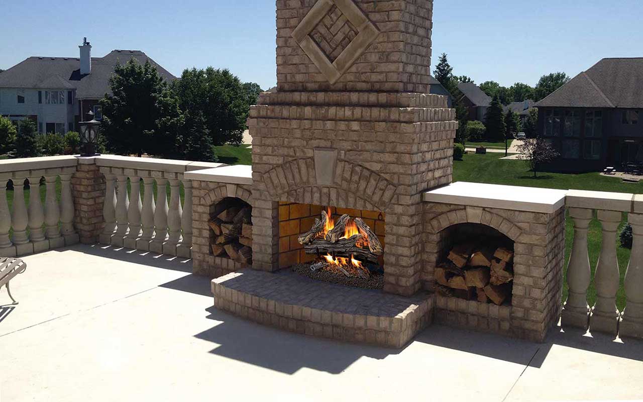a large brick fireplace is sitting on a patio next to a house .