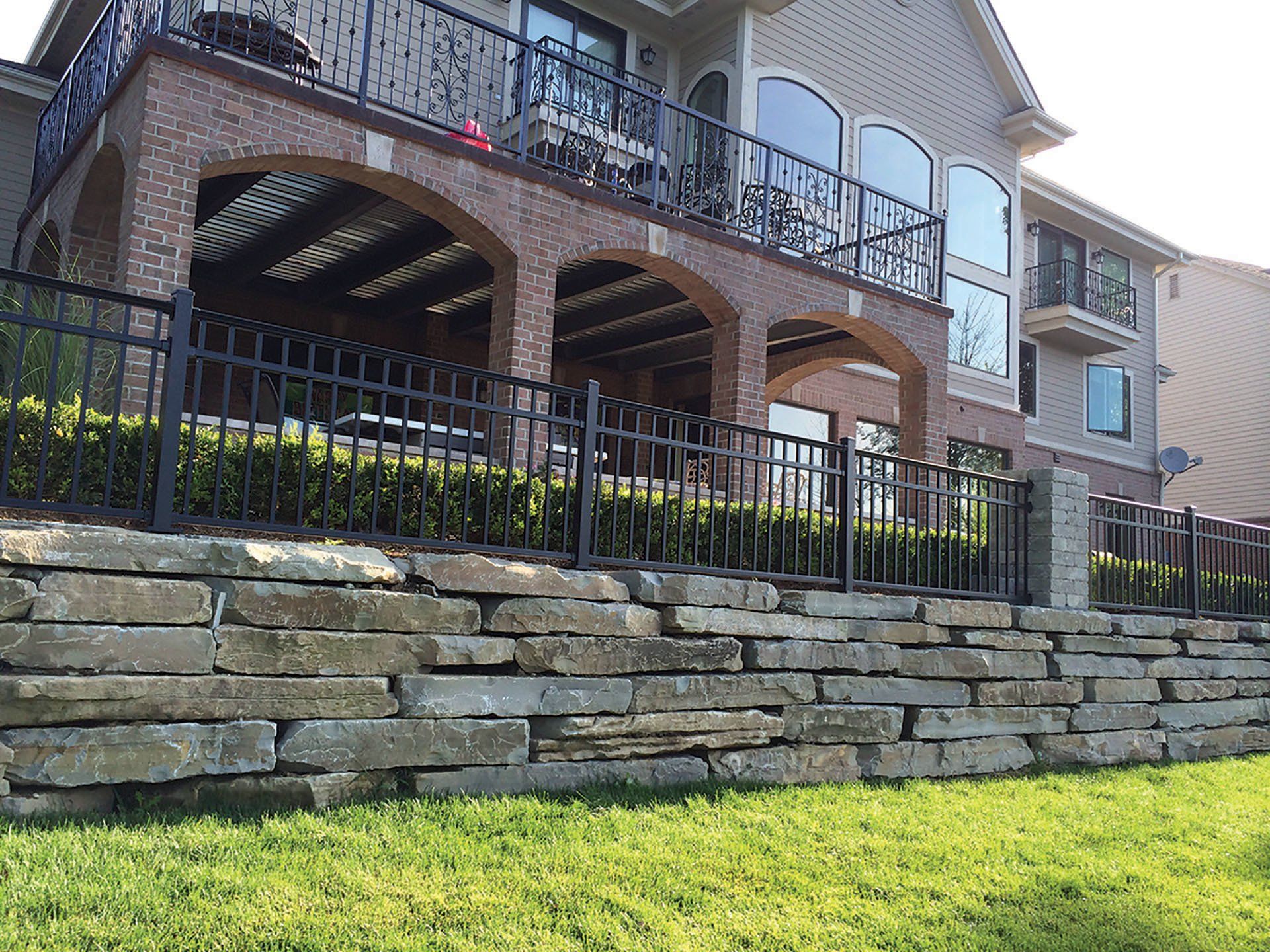 a large house with a balcony and a stone wall behind it .