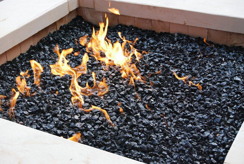 a fire pit filled with black rocks and flames