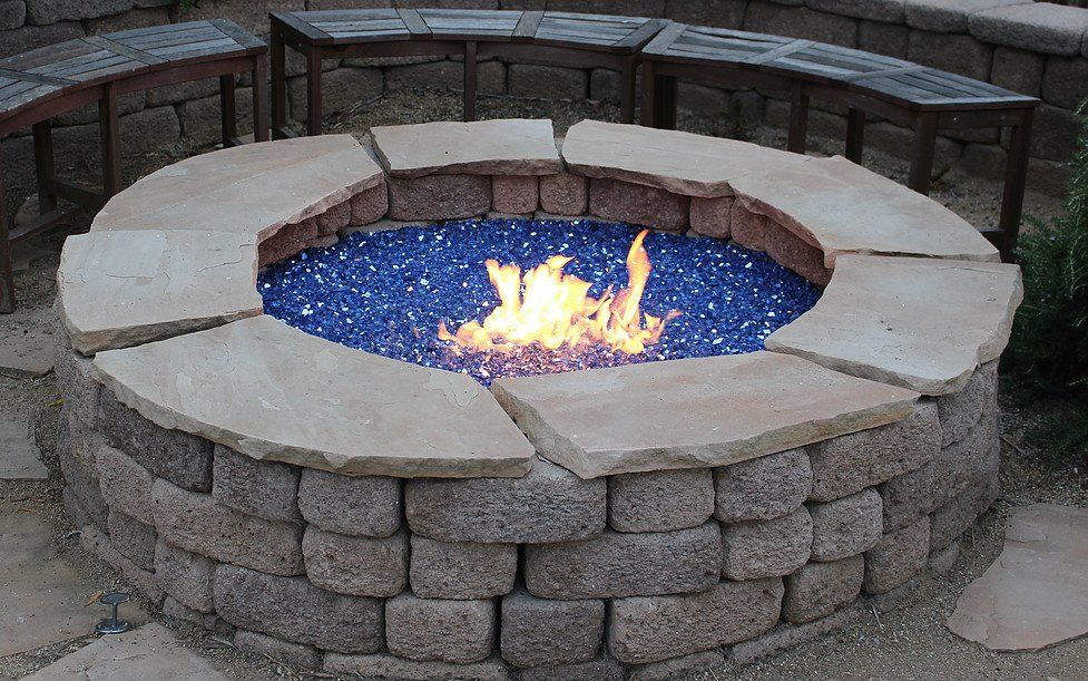 a fire pit surrounded by bricks and blue glass beads