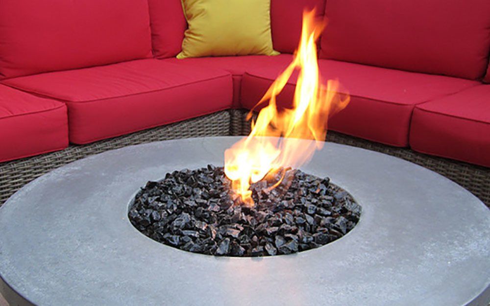 a fire pit is sitting in front of a couch with red cushions .