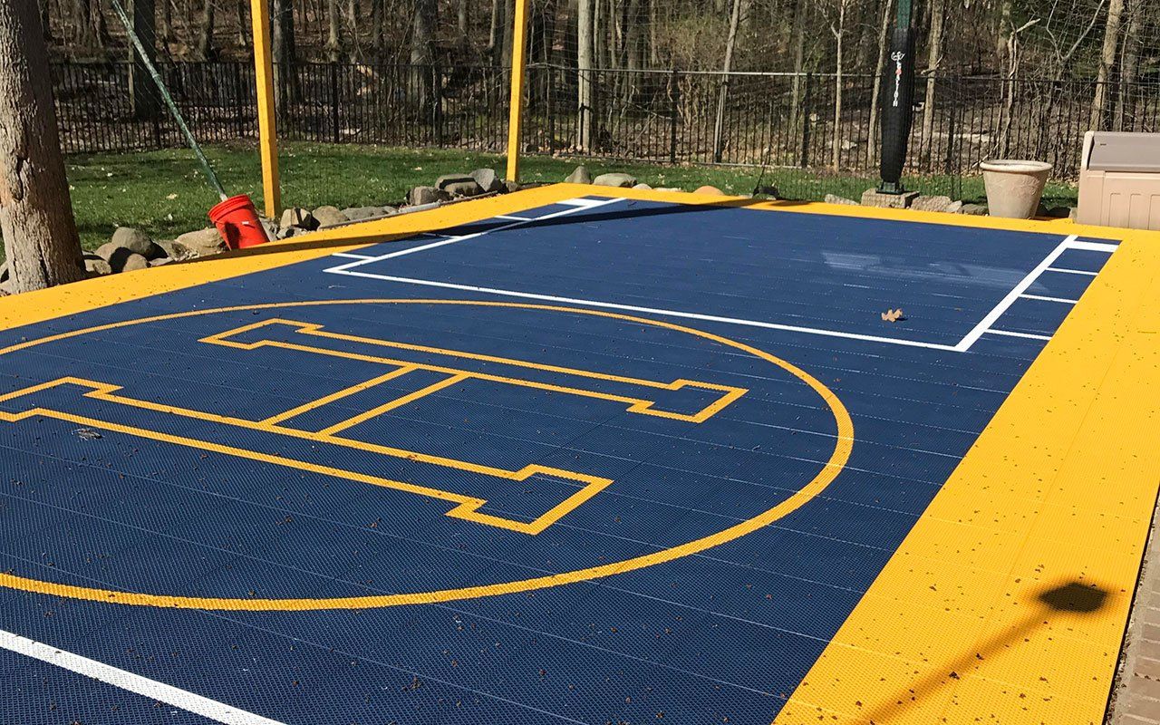 A blue and yellow basketball court with a logo on it.