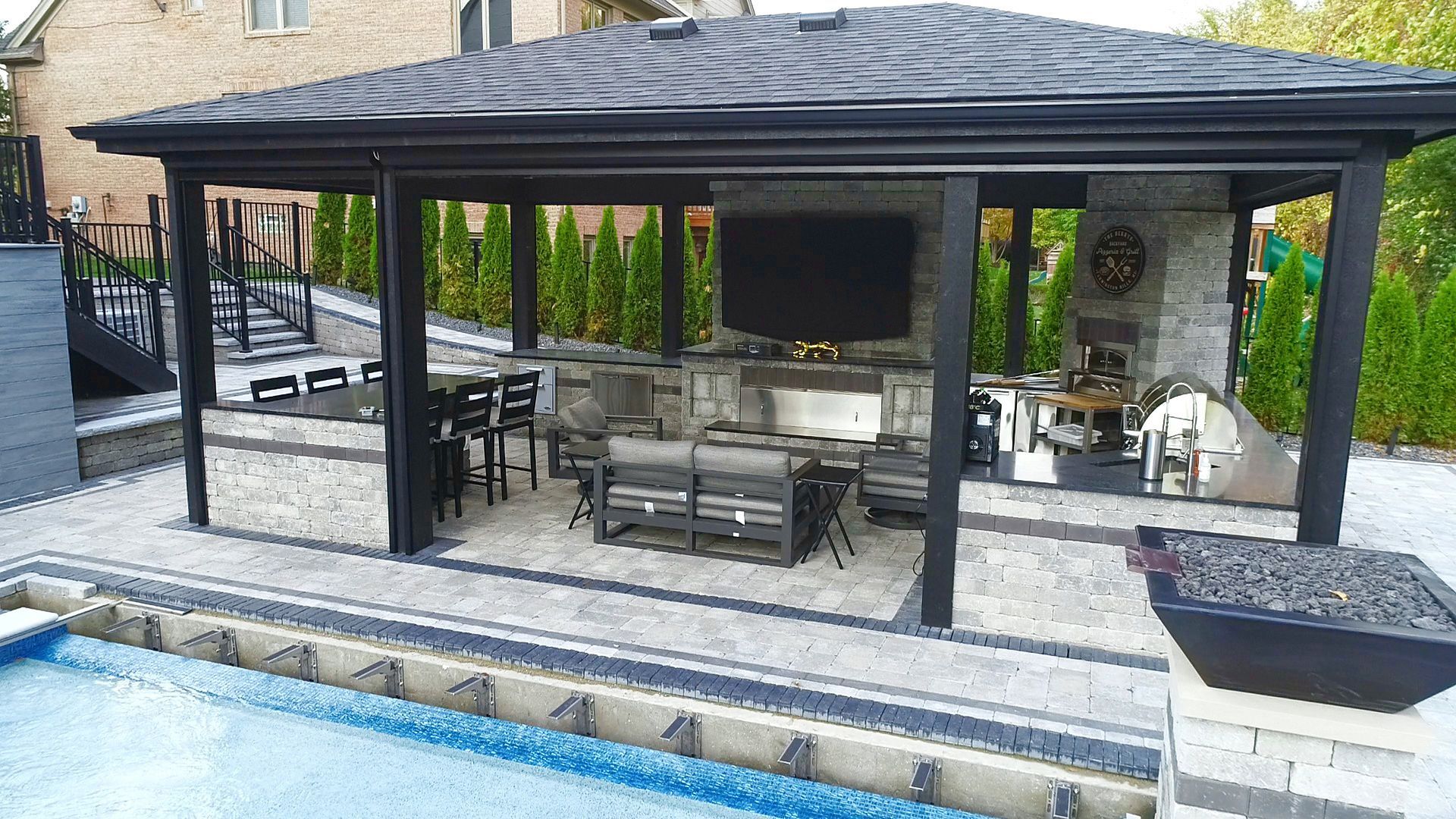 a covered patio with a television and a fireplace next to a pool .