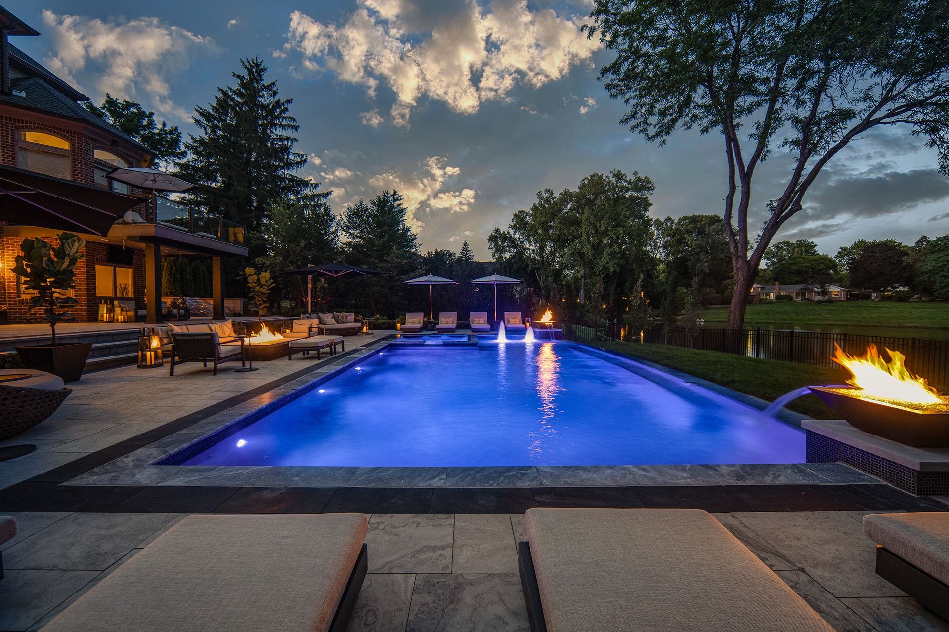 a large swimming pool with blue lights and a fire pit in the backyard .