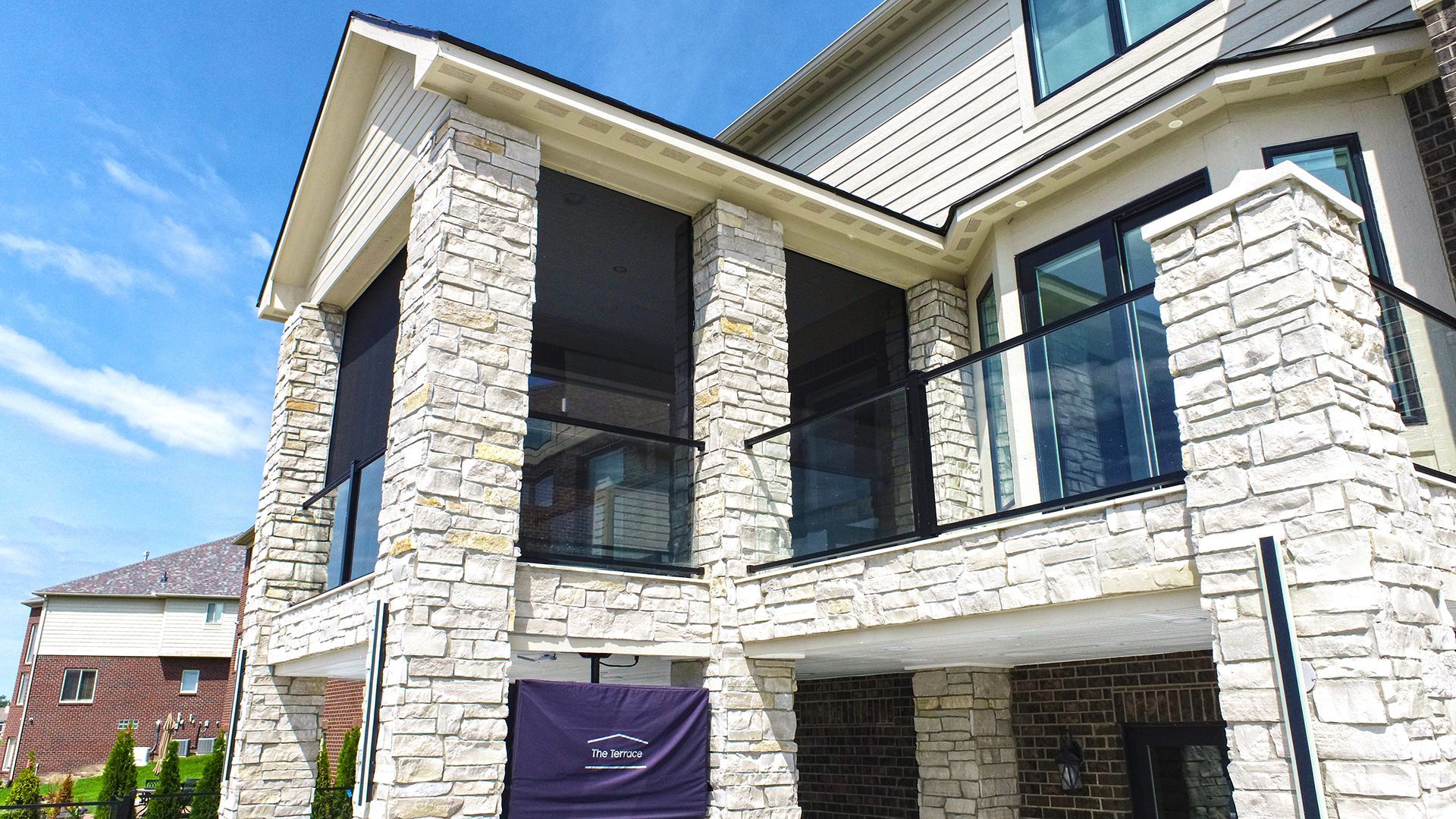 a large white brick house with a balcony and a blue sky in the background .