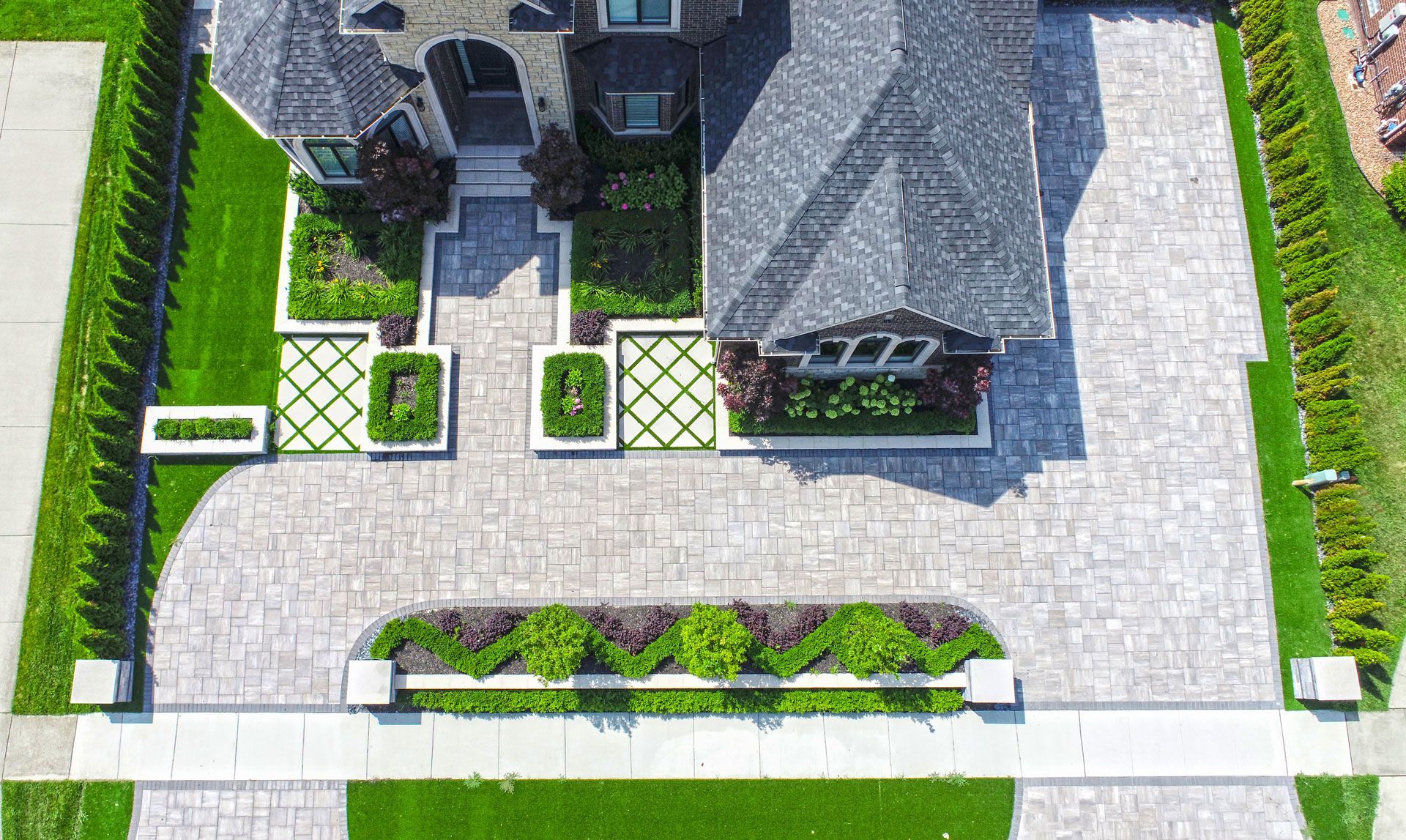 an aerial view of a house with a driveway and a lush green lawn .