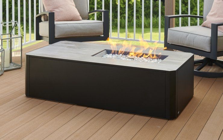 a fire pit is sitting on a wooden deck next to two chairs .