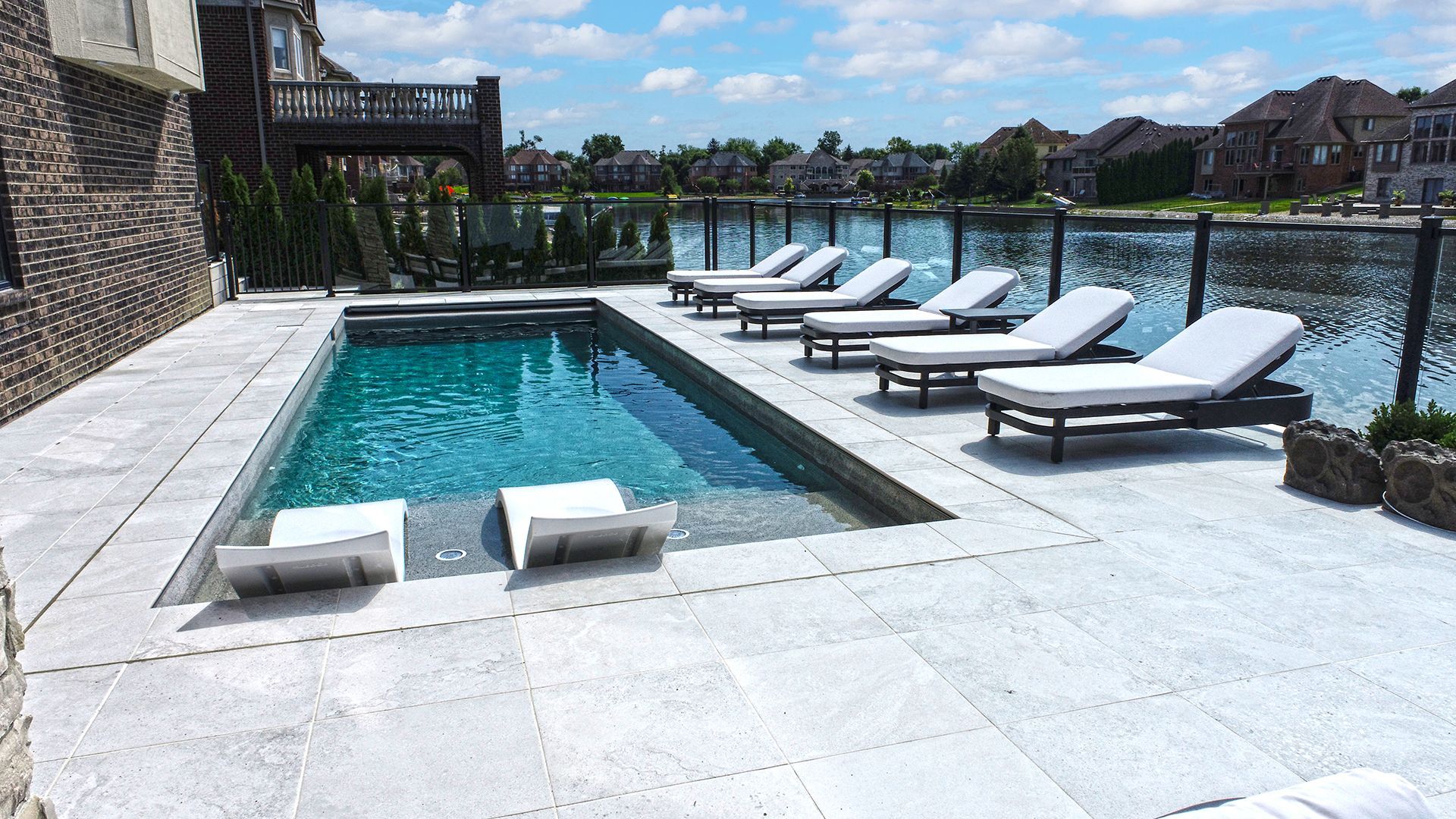 a large swimming pool surrounded by lawn chairs and a lake .
