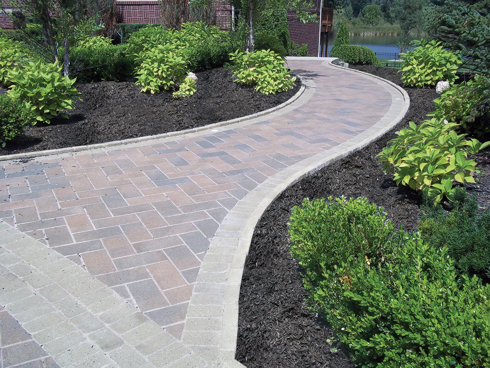 a brick walkway is surrounded by trees and bushes