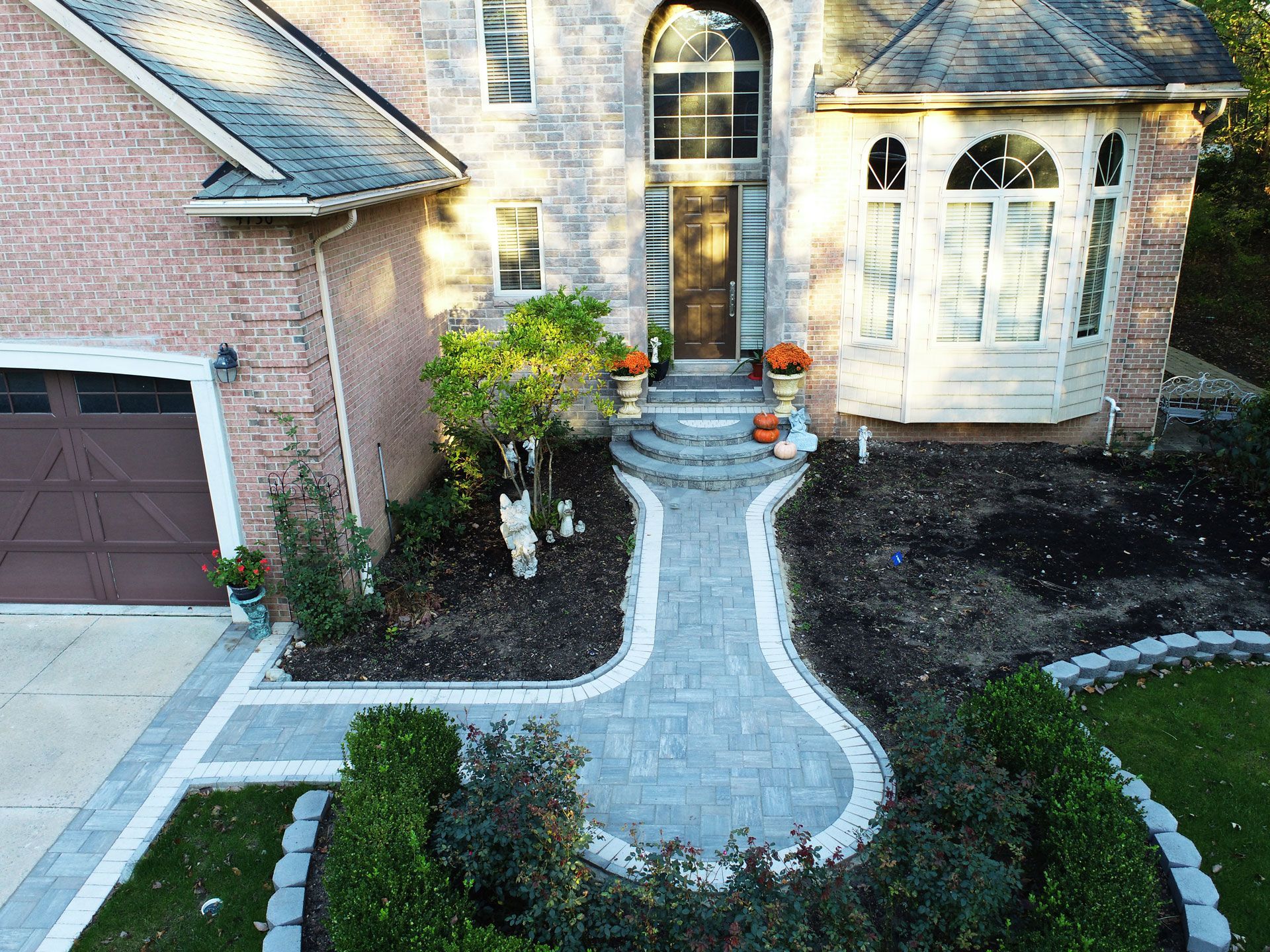 an aerial view of a brick house with a walkway leading to the front door .