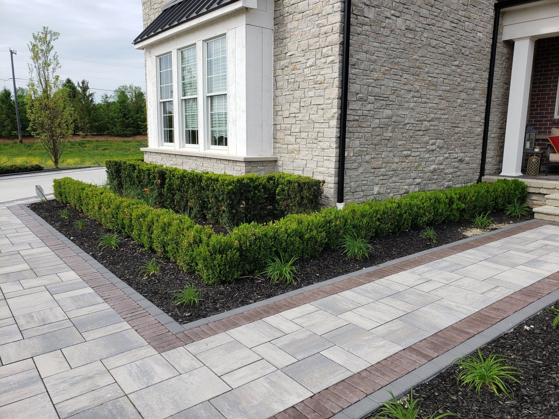 a brick walkway leading to a house with a garden in front of it .