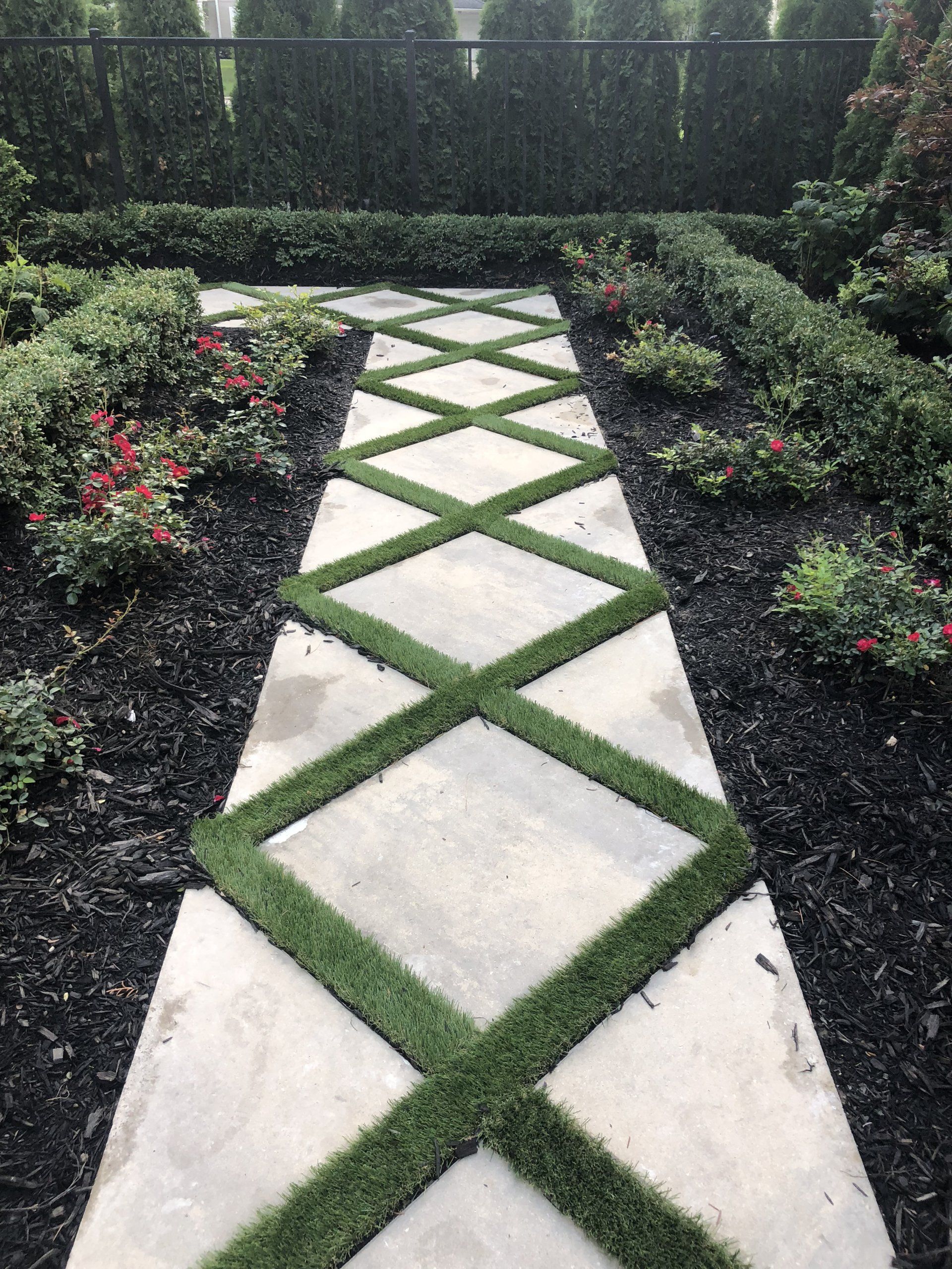 a concrete walkway with a pattern of grass on it