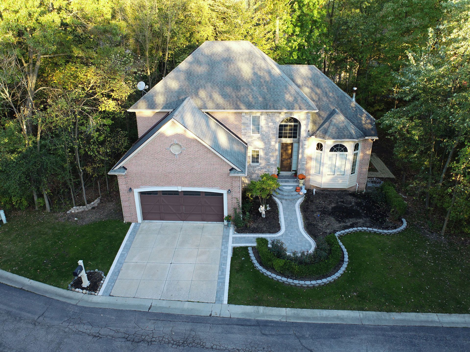 an aerial view of a large brick house with a large driveway surrounded by trees .