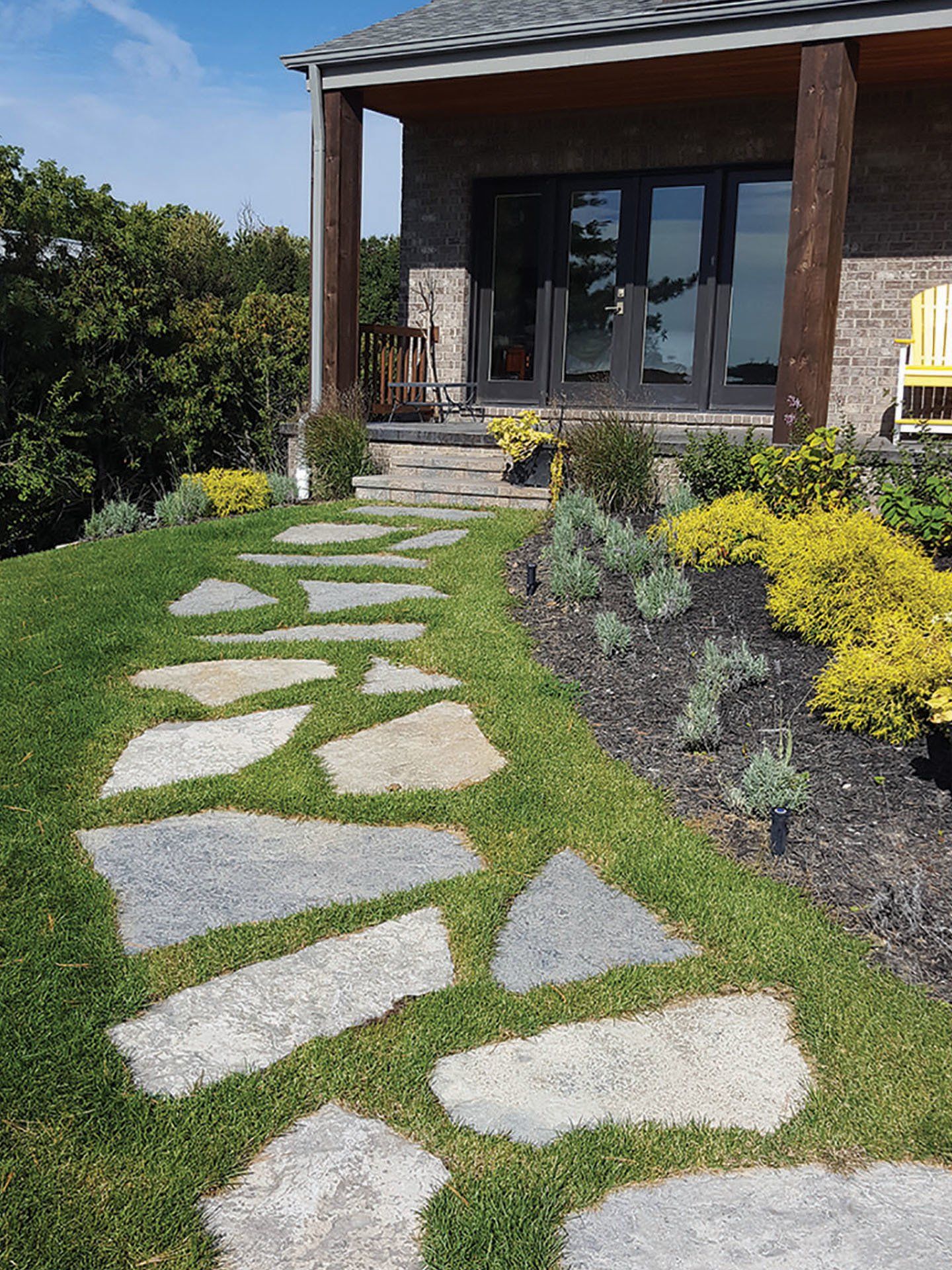 a stone walkway leading to a house with a porch