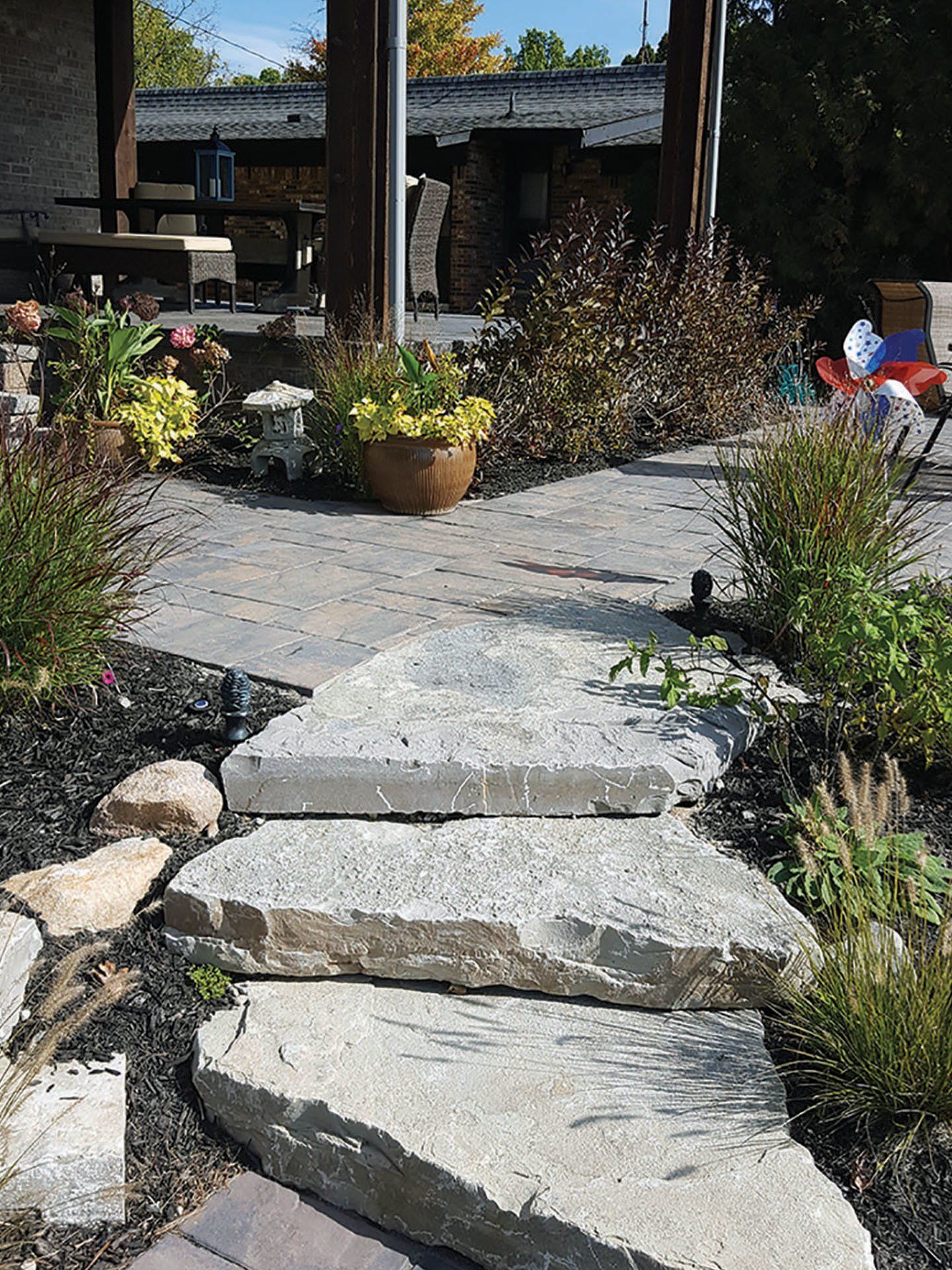 a stone walkway leading to a patio with a house in the background .