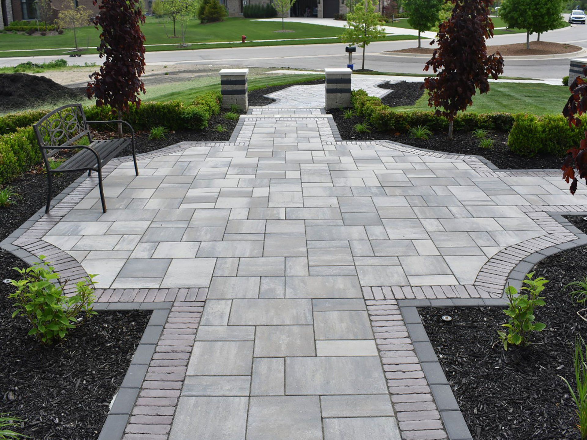 a brick walkway with a bench in the middle