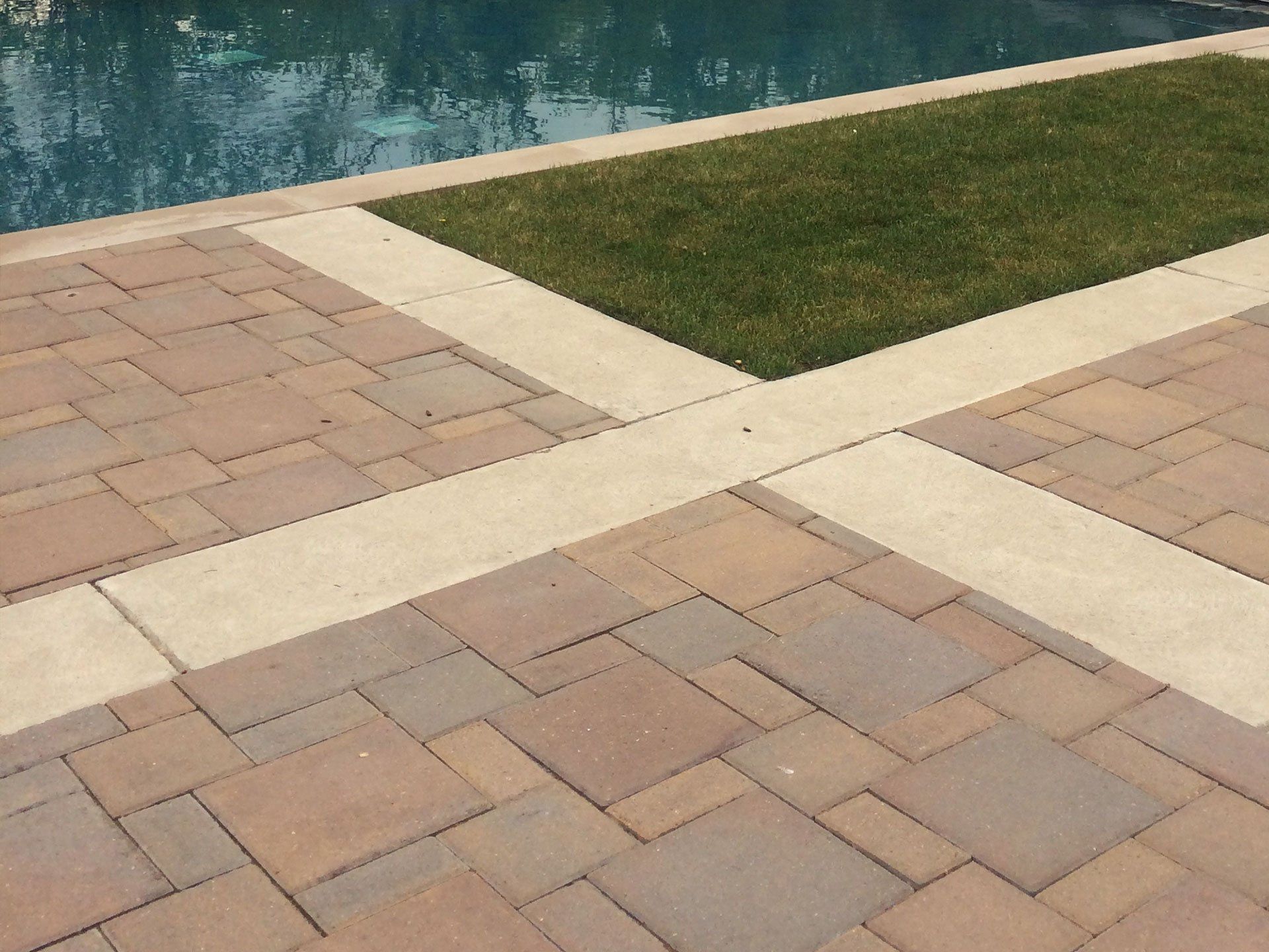a brick walkway next to a swimming pool