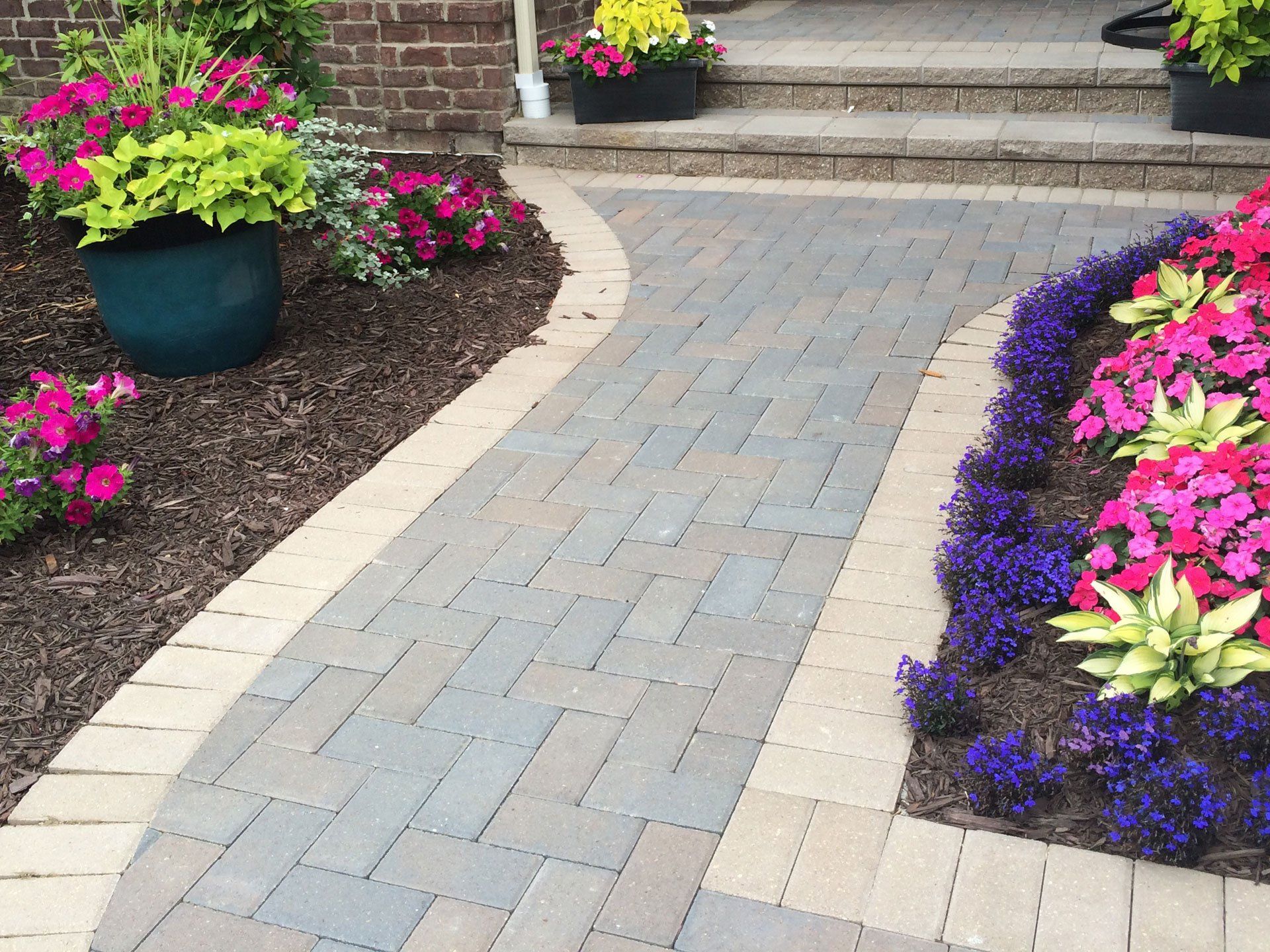 a brick walkway surrounded by potted plants and flowers