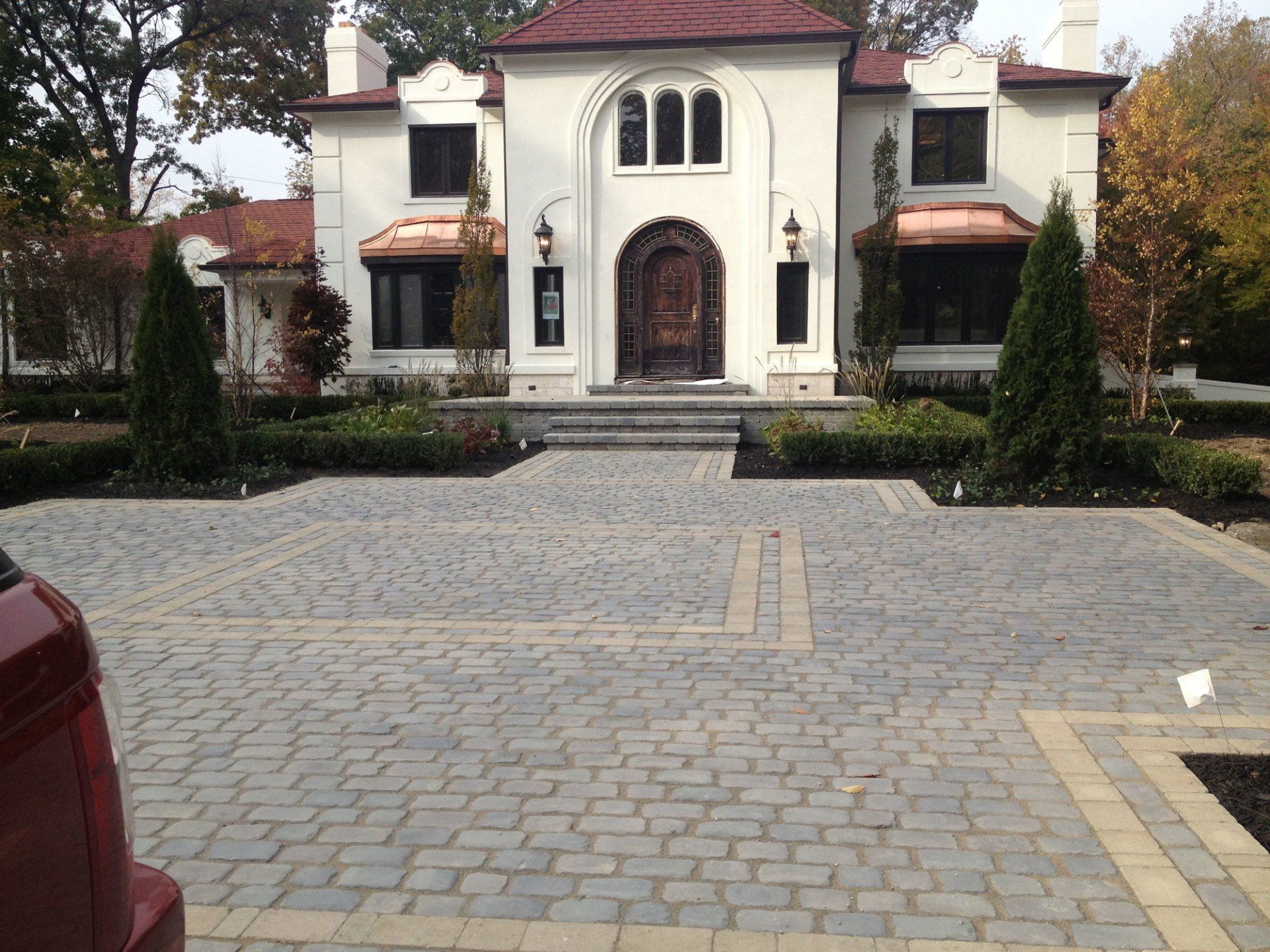 a cobblestone driveway in front of a house with two garage doors .