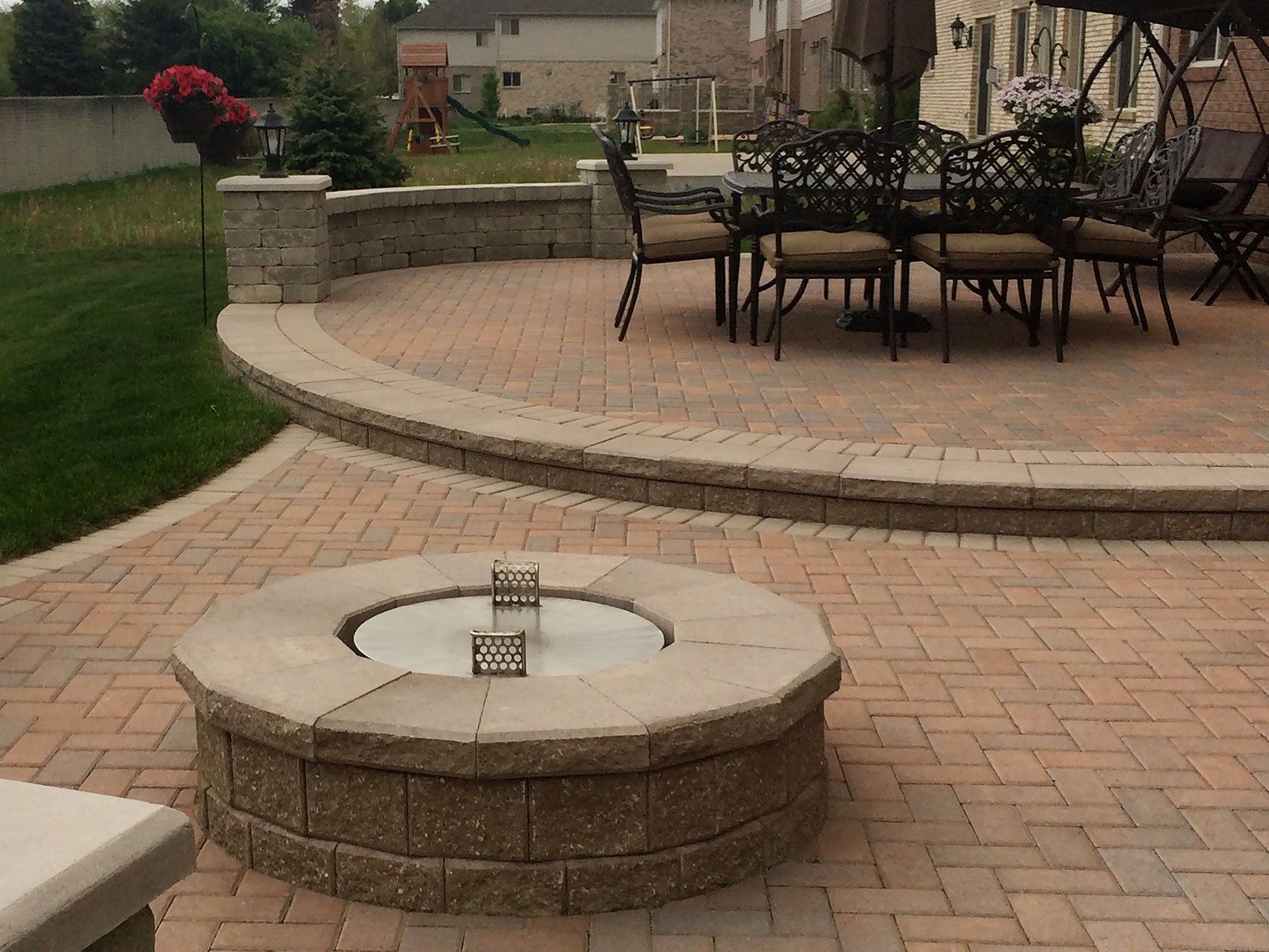 a brick patio with a fire pit and a table and chairs