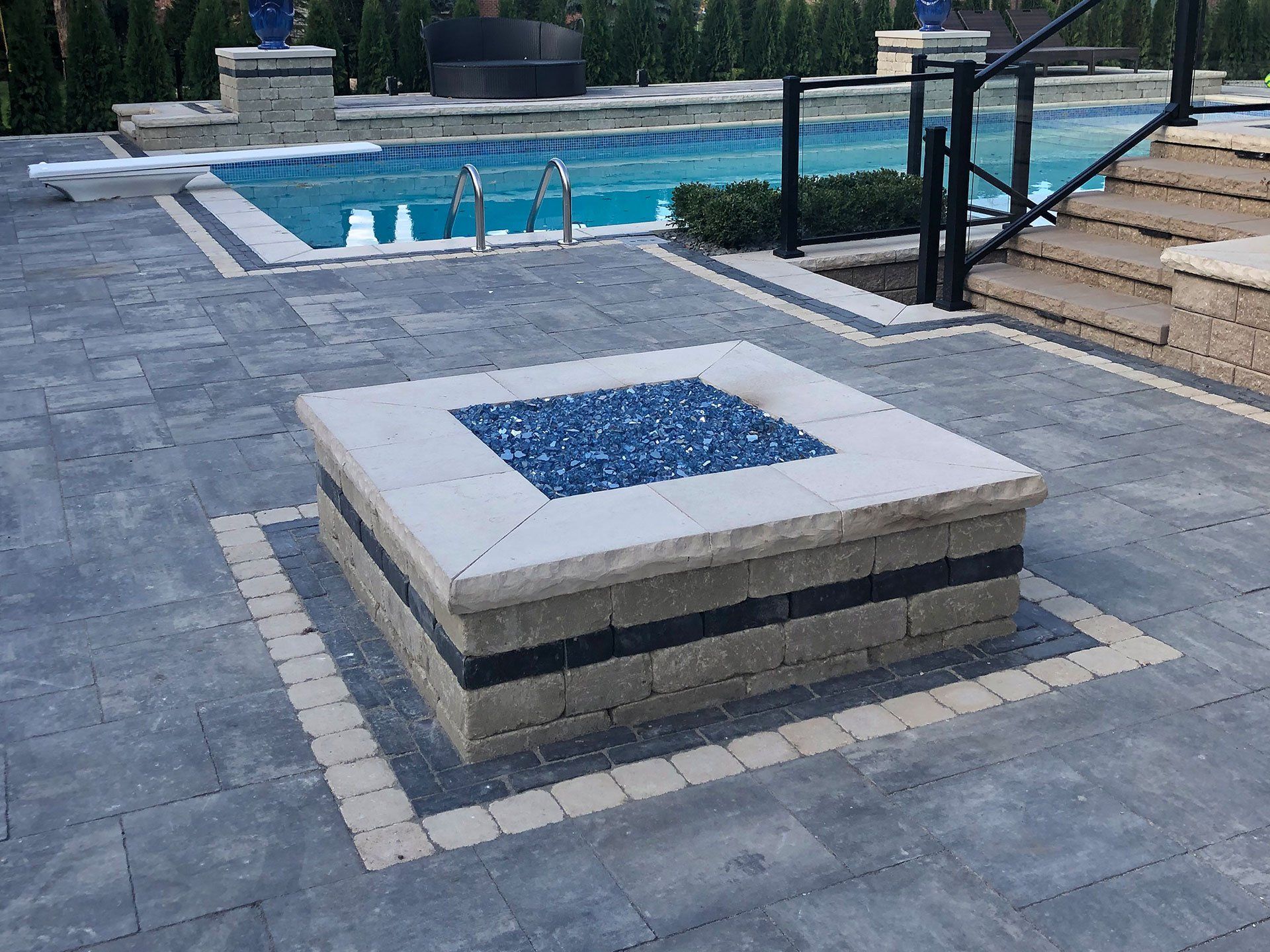 a fire pit is in the middle of a patio next to a pool .