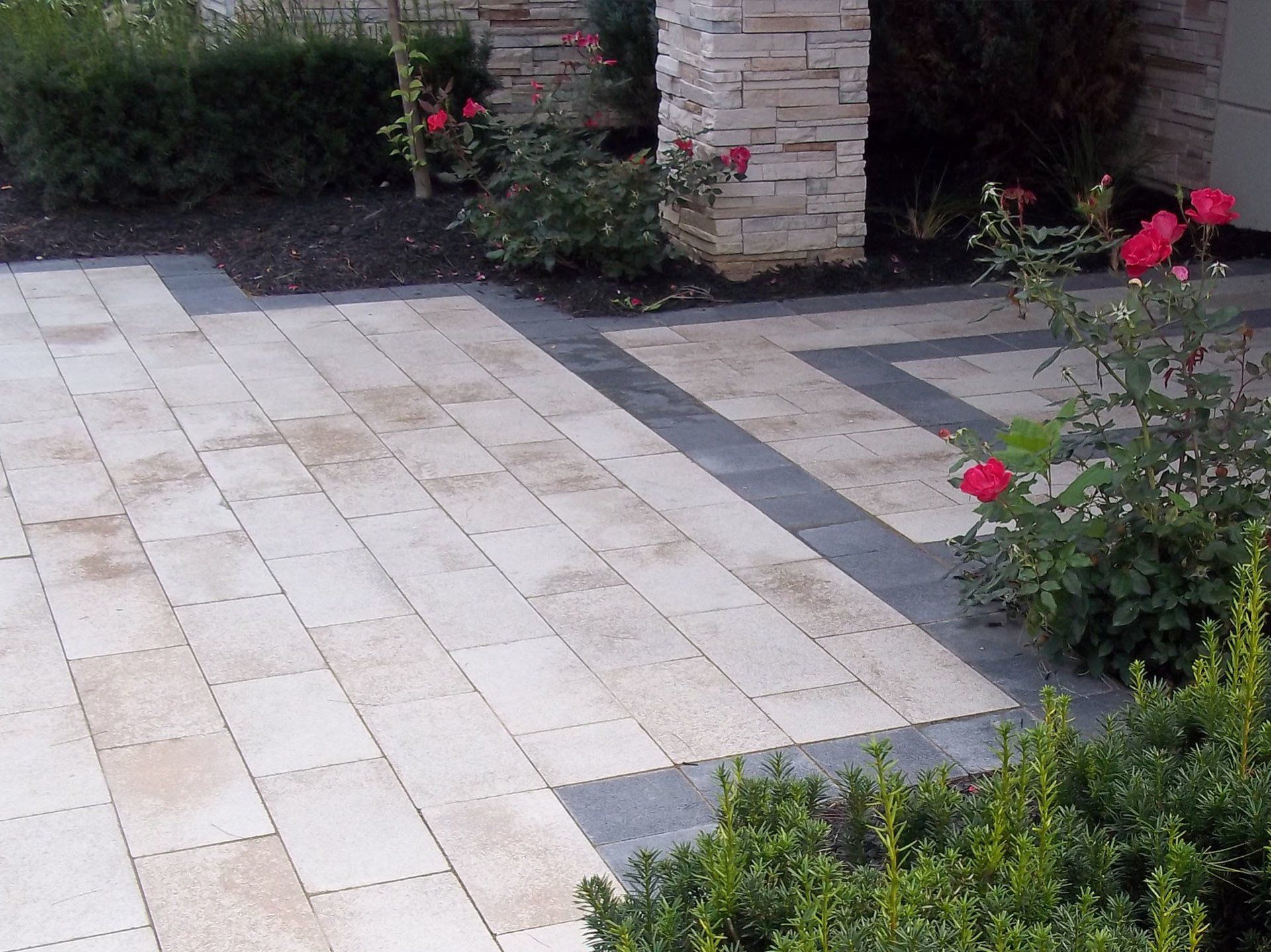 a brick walkway with flowers in the background