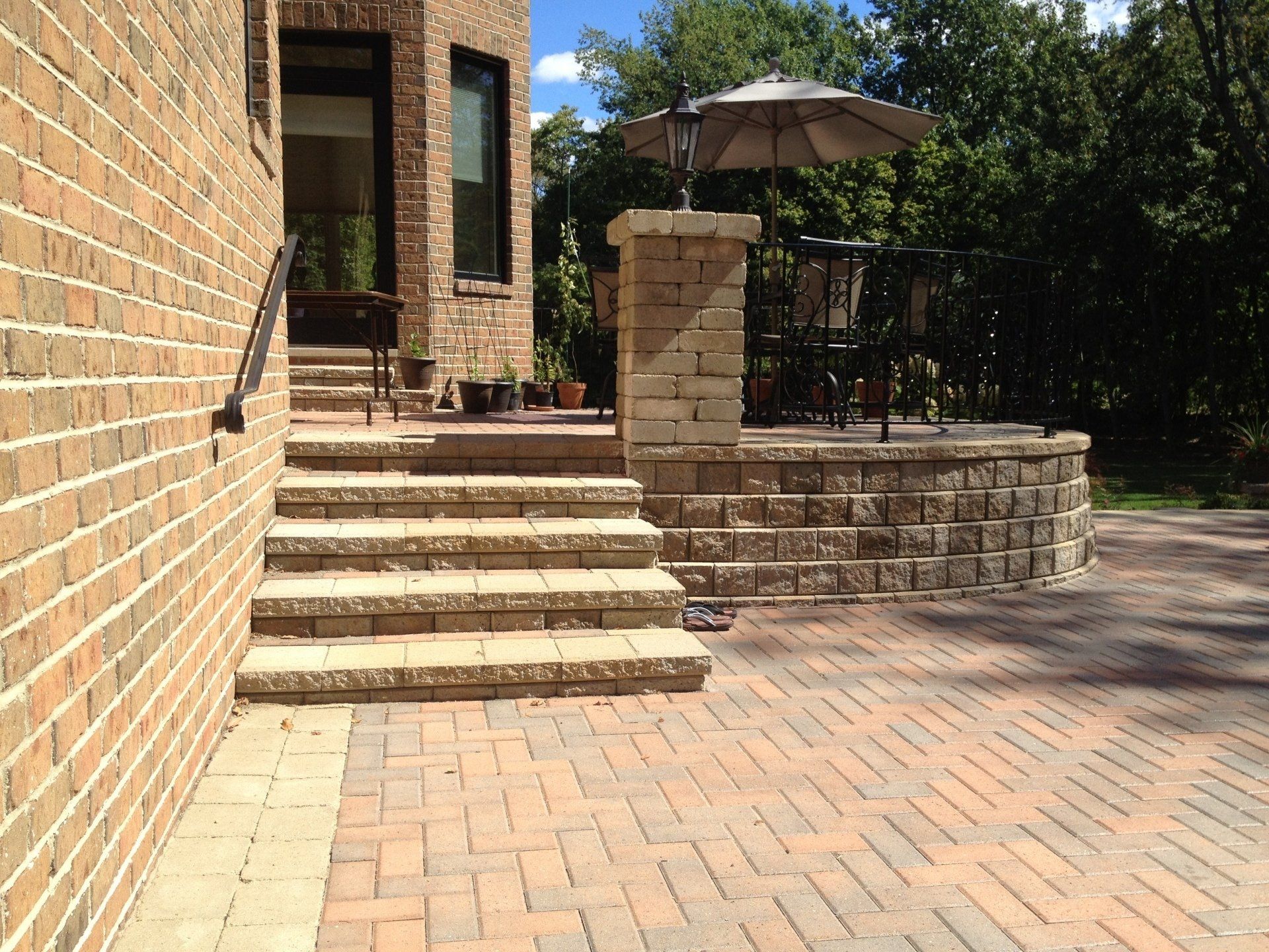 a brick house with stairs and a patio with an umbrella