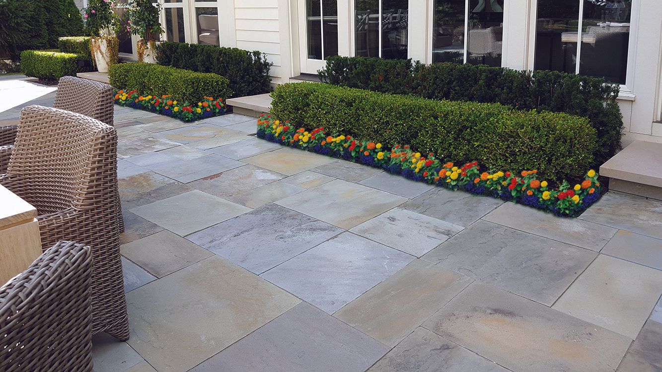 a patio with wicker chairs and flowers in front of a house .