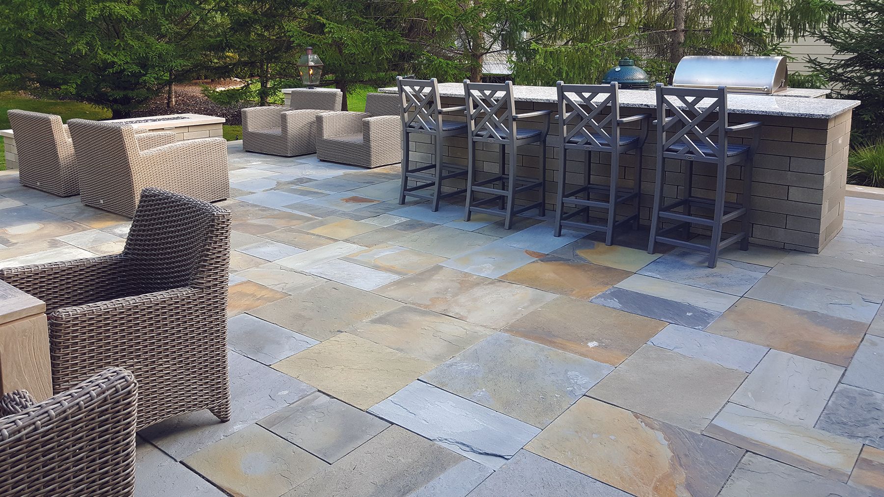 A patio with wicker chairs and a grill